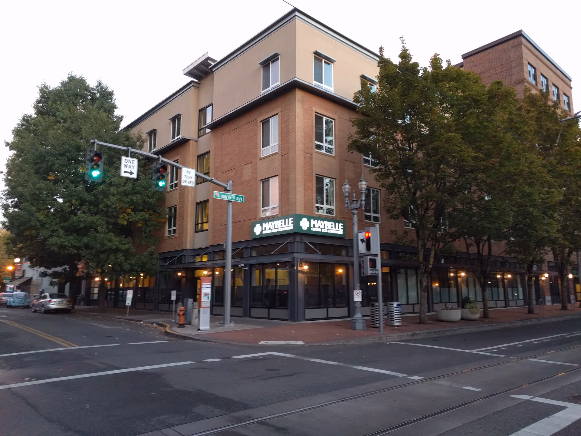 Corner street view of a brick building with storefront windows and trees.