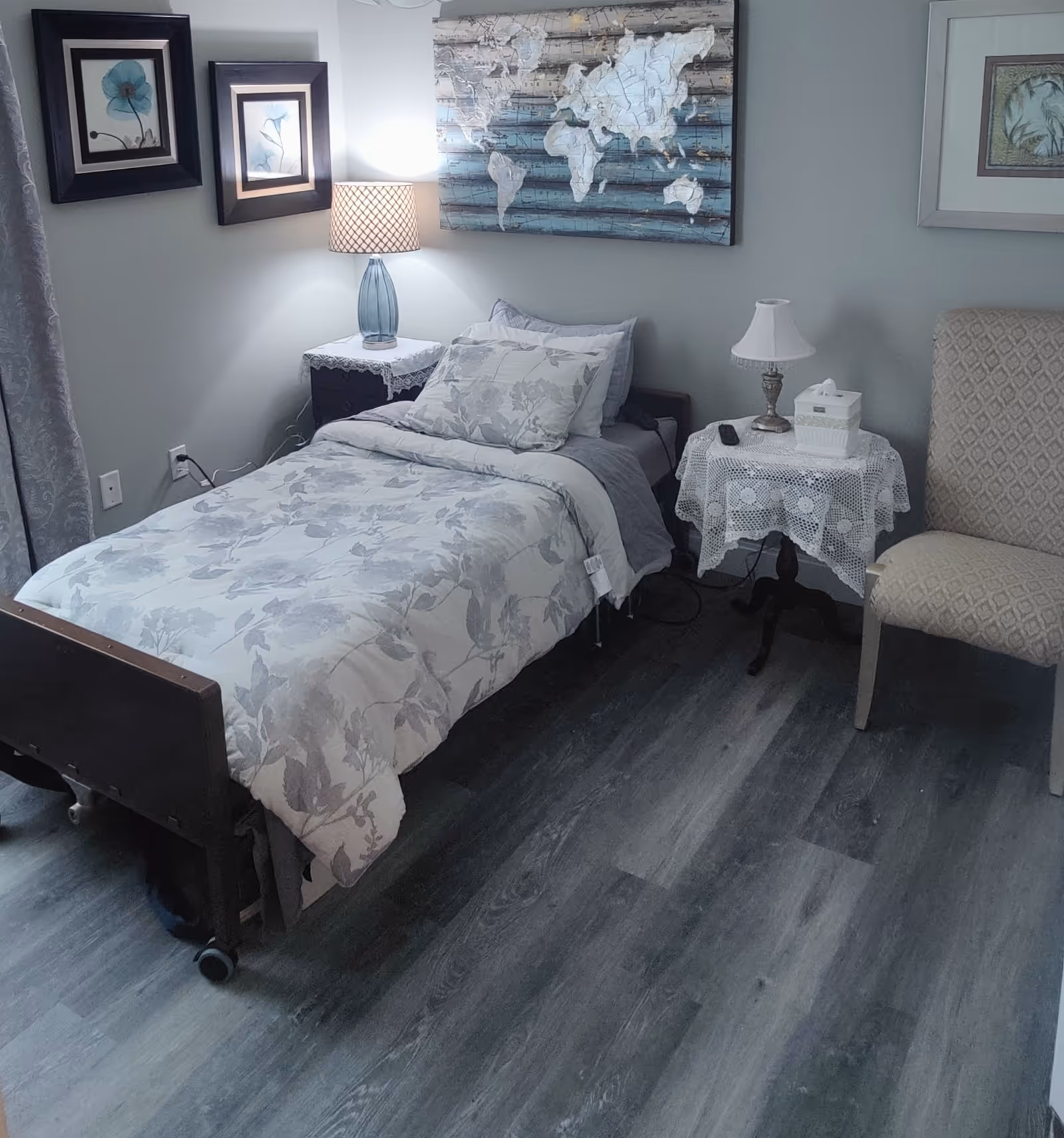 A furnished bedroom with a single adjustable bed, nightstands, lamps, and framed art.