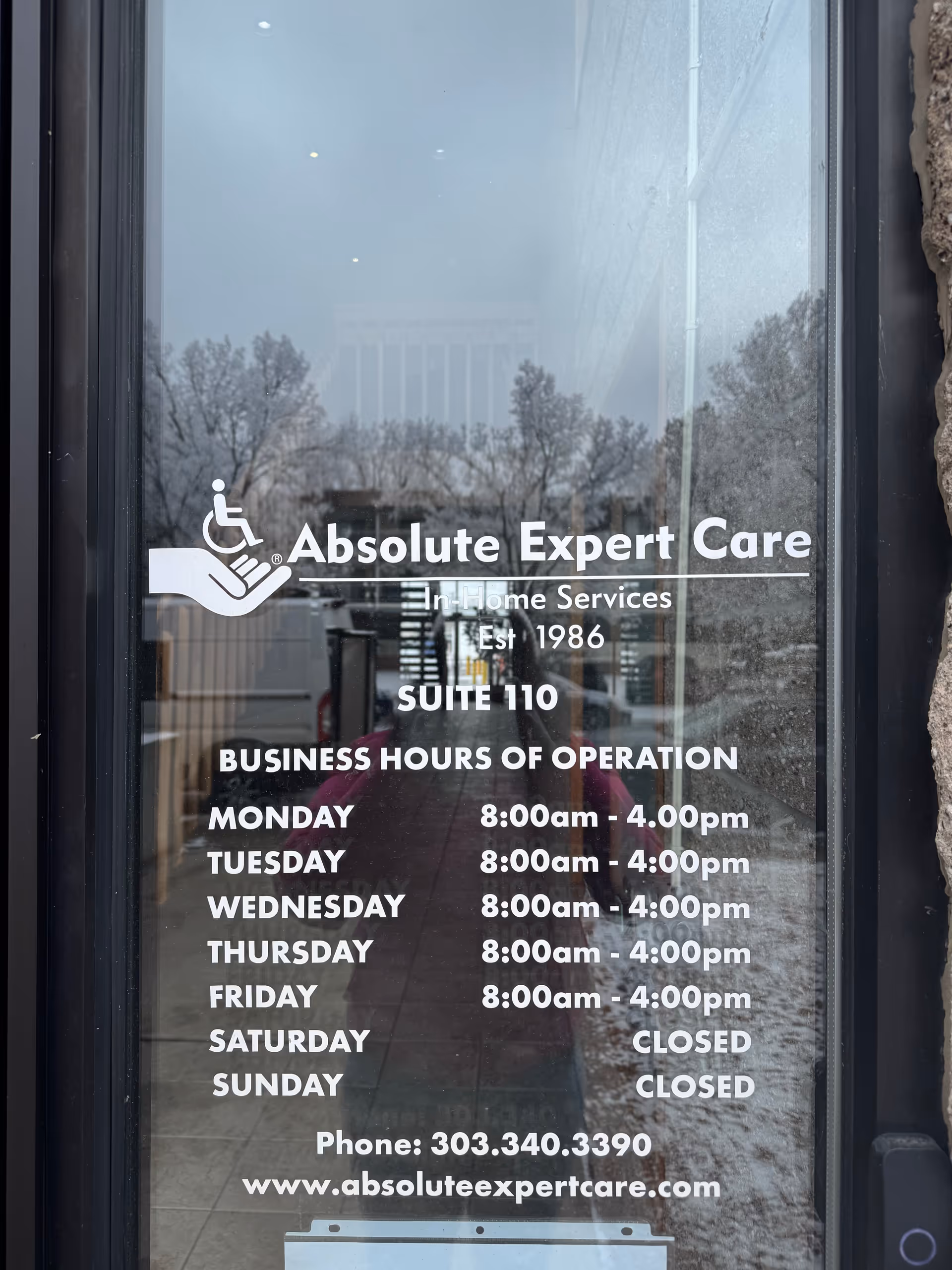 Glass door with Absolute Expert Care sign and business hours display.