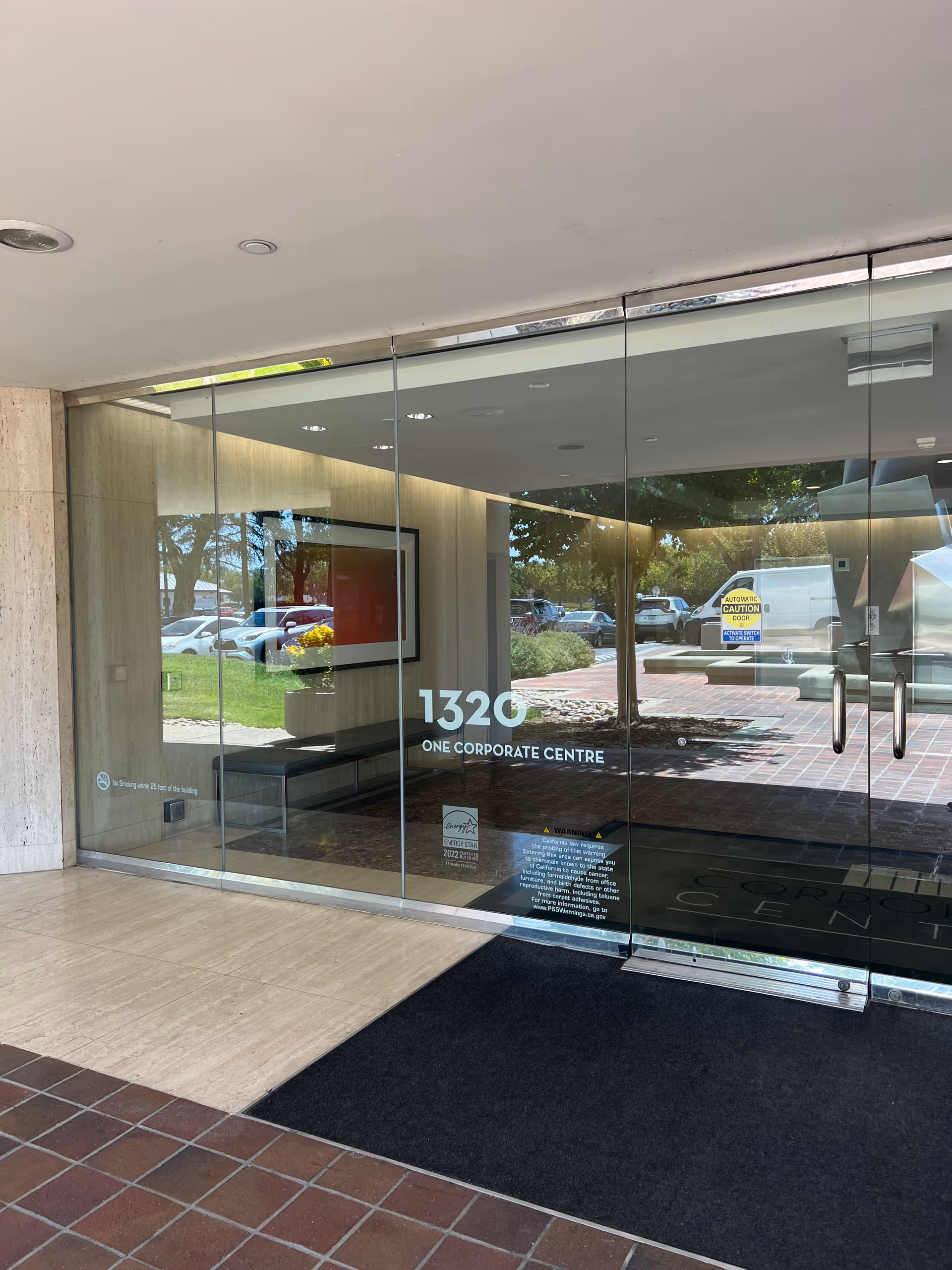 Glass front entrance of a corporate building with 1320 One Corporate Centre signage.