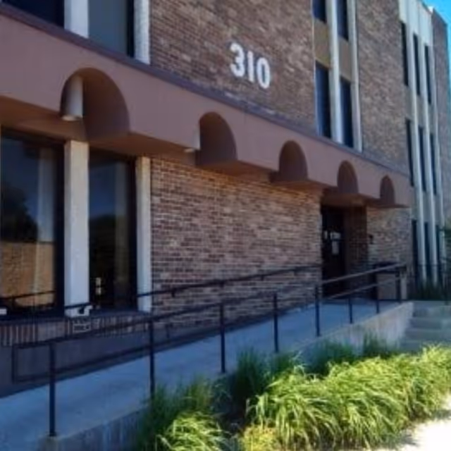 Exterior of a brick building with arched awnings, ramp, and the number 310.