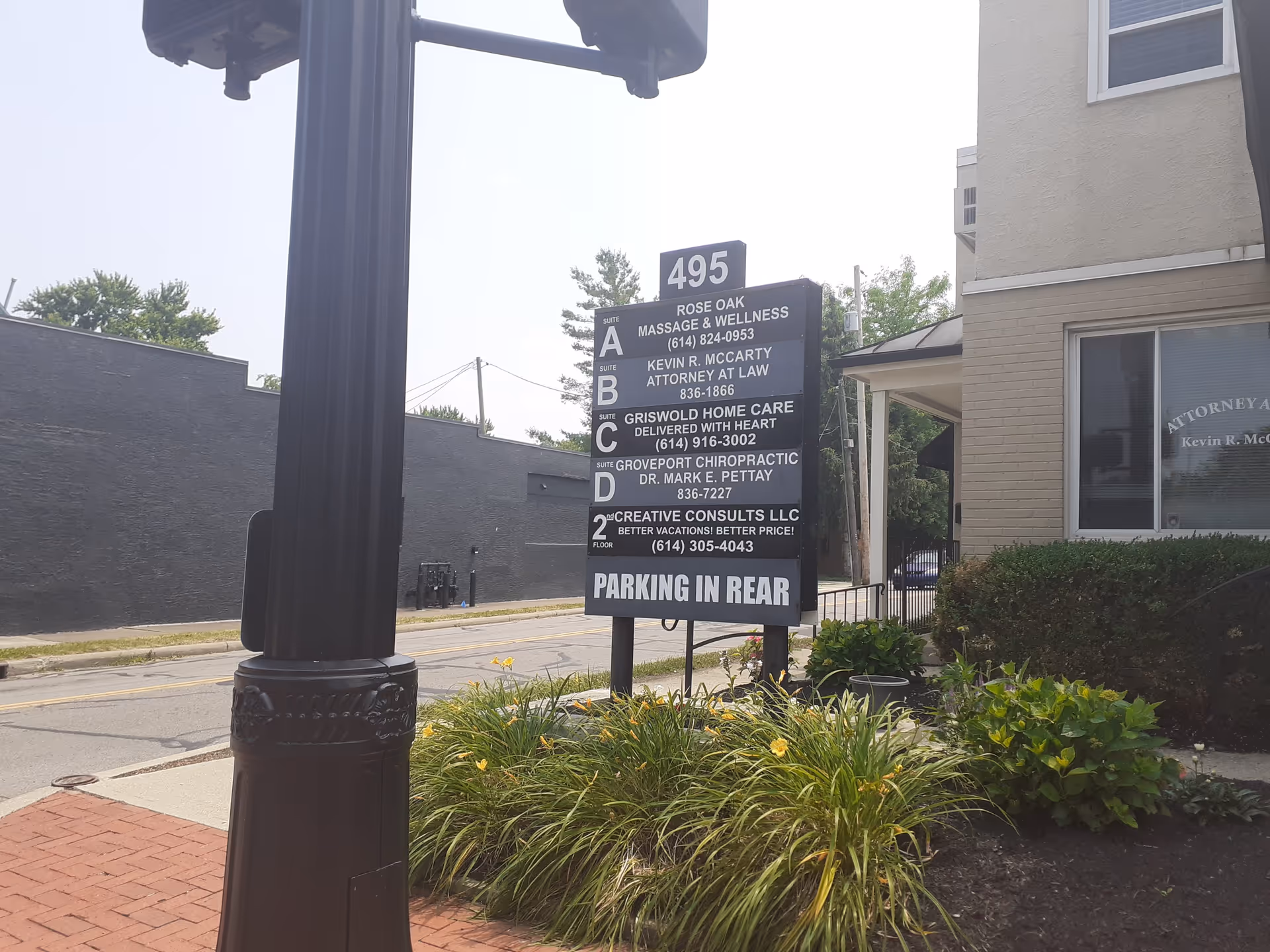 Outdoor street view with a tall signboard listing Griswold Home Care near a building.
