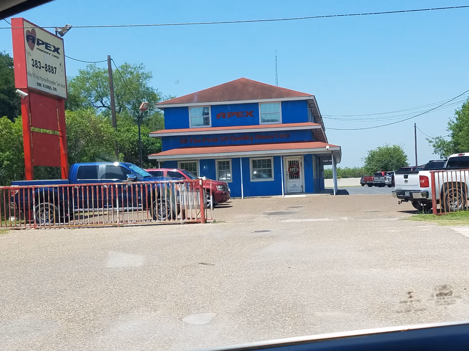 Blue Apex Primary Care building with red trim and surrounding parking lot.