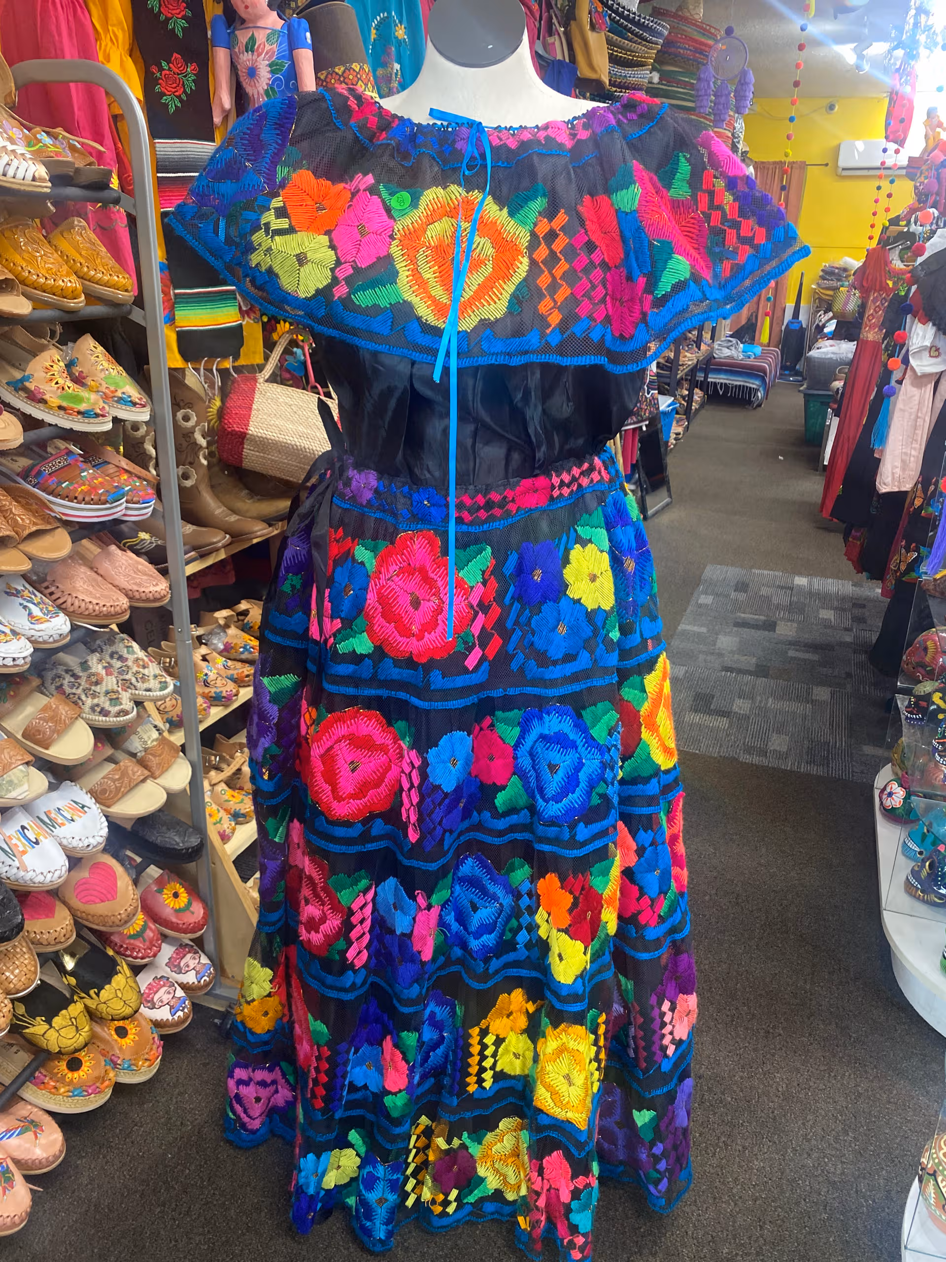Colorful embroidered dress on a mannequin inside a clothing store.