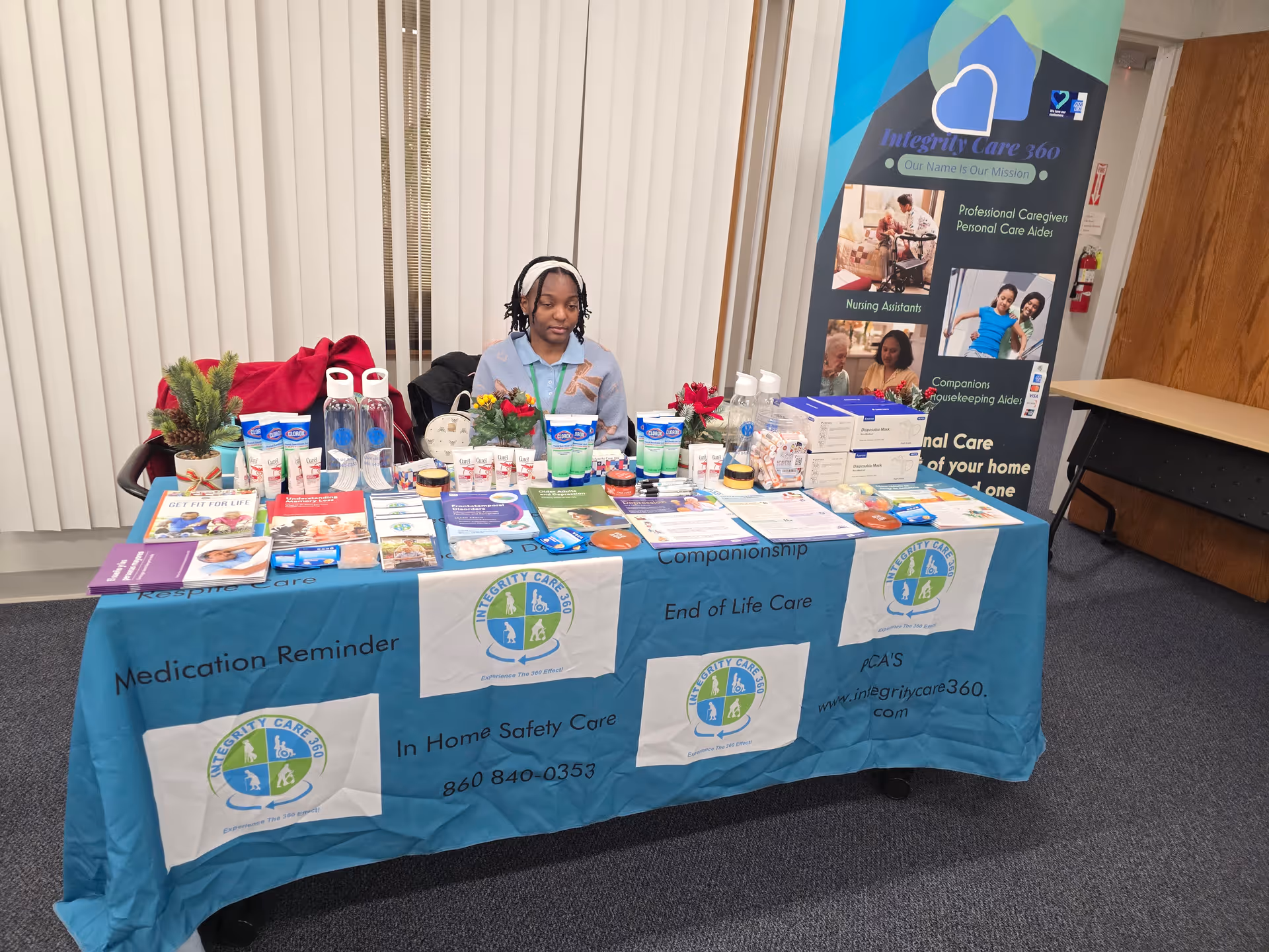 A woman sits behind a table of healthcare brochures at an Integrity Care 360 booth.