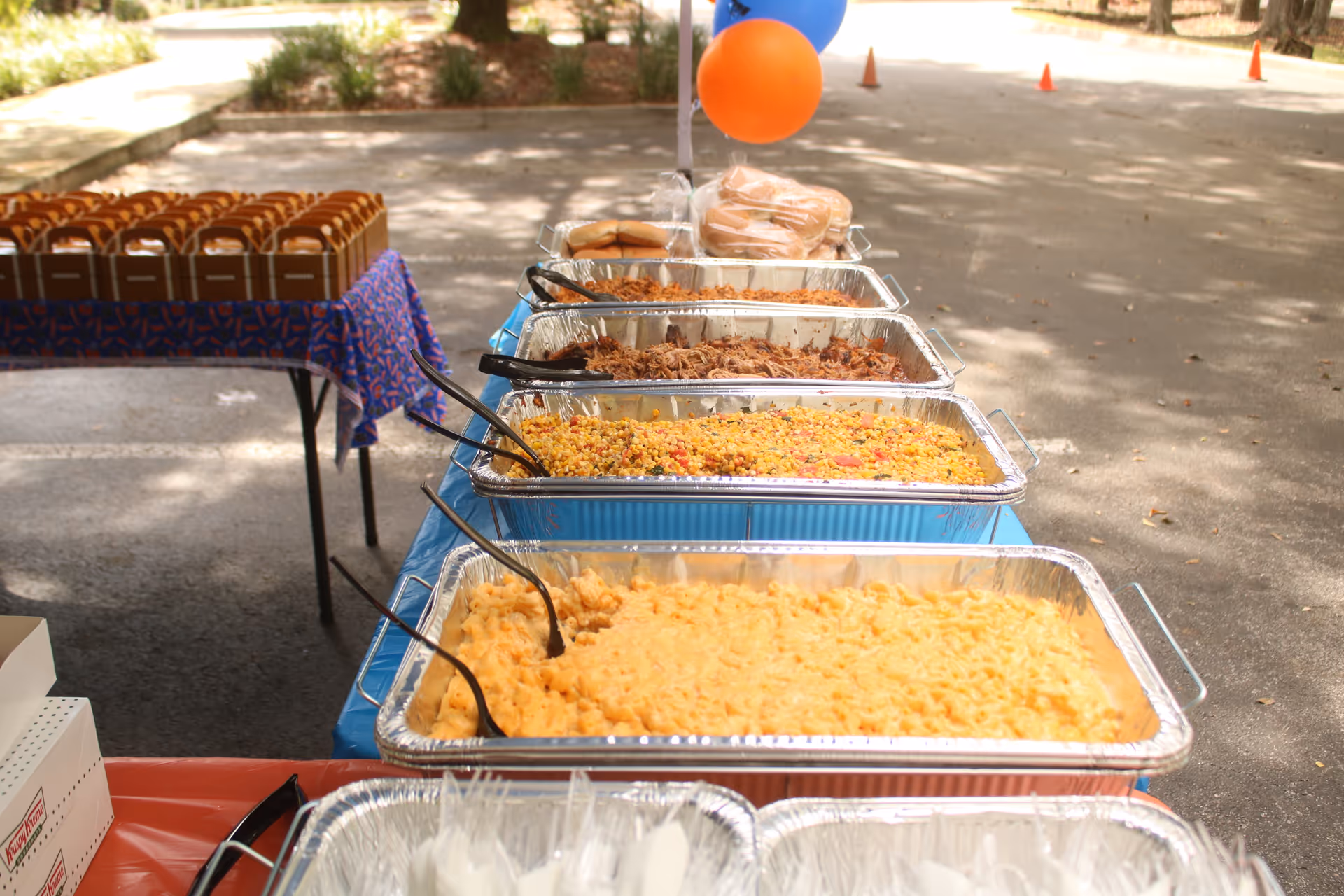 Outdoor buffet setup with aluminum chafing dishes containing assorted hot entrees.