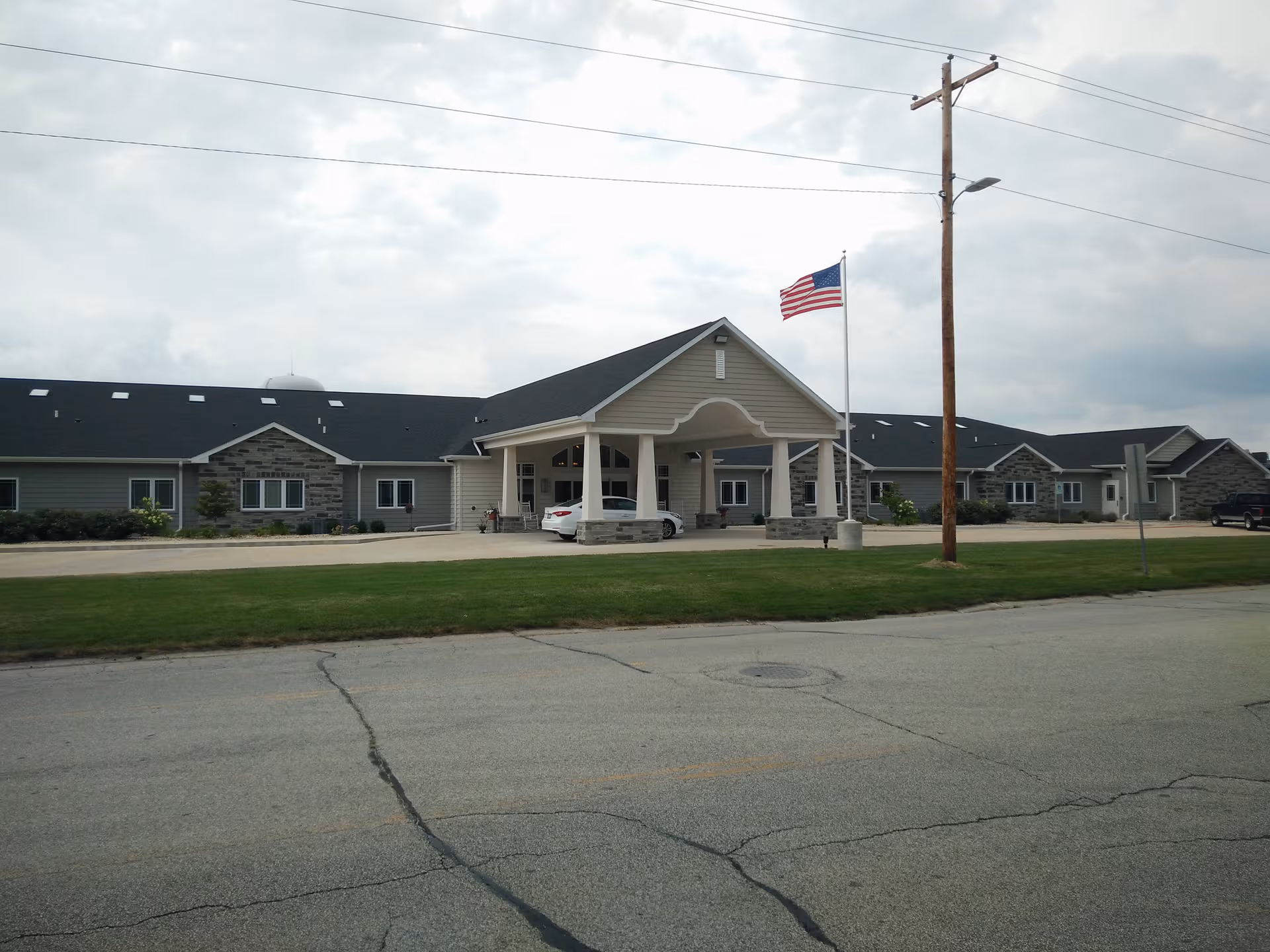 Reflections Memory Care facility exterior with front entrance and American flag