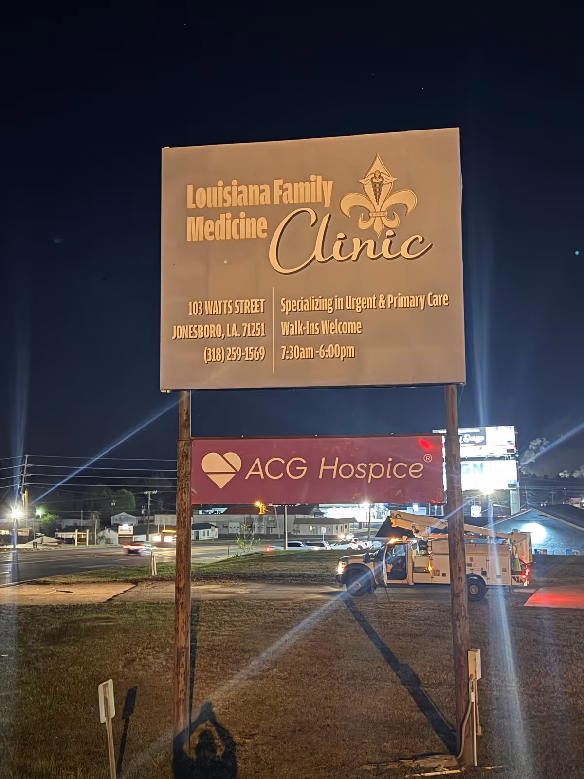 Nighttime exterior sign displaying Louisiana Family Medicine Clinic and ACG Hospice.