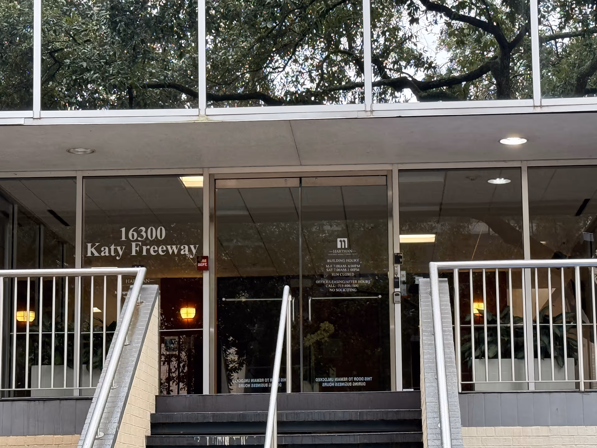 Front entrance with glass doors, stairs, and metal railings.