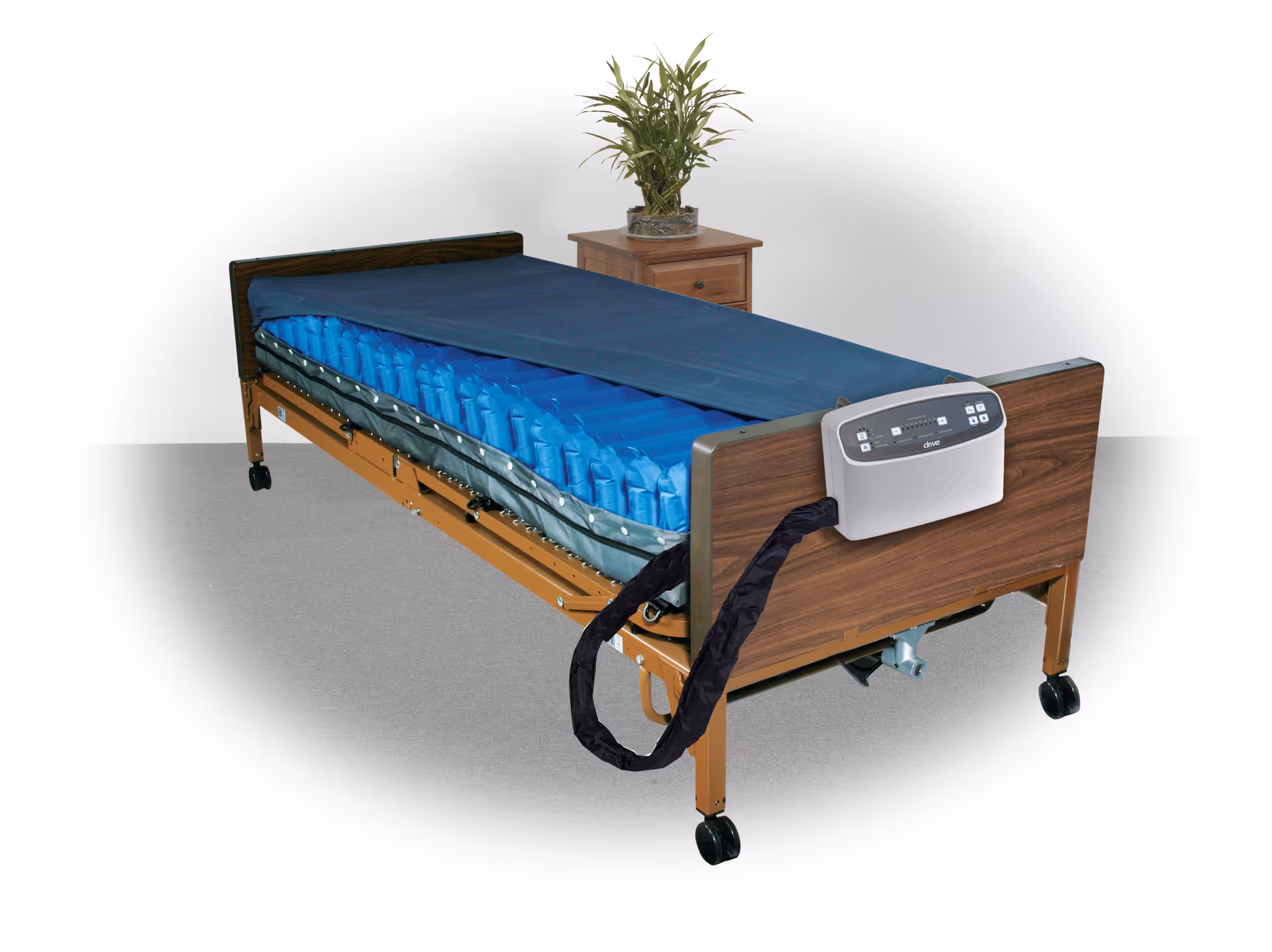 Adjustable hospital bed with blue mattress and a nightstand in a bedroom.