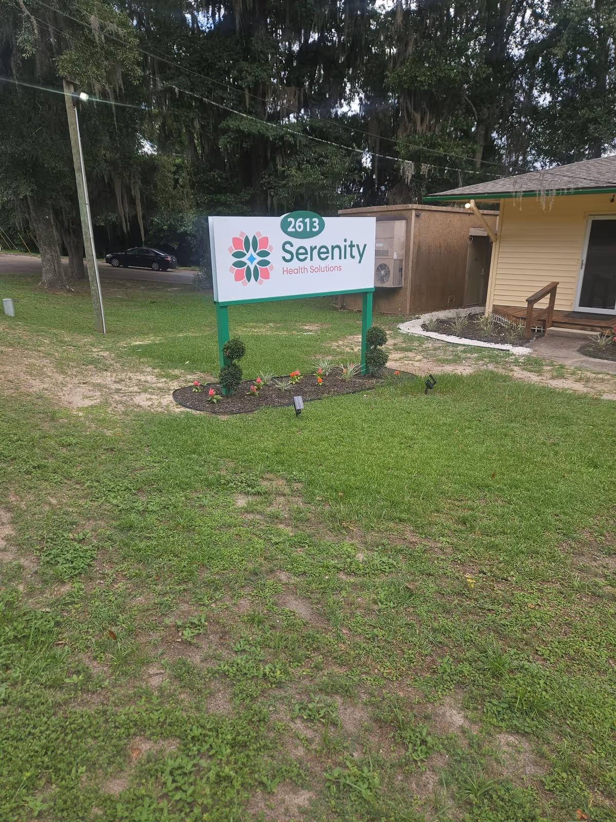 Serenity Health Solutions sign at the front of a small beige building with a manicured lawn
