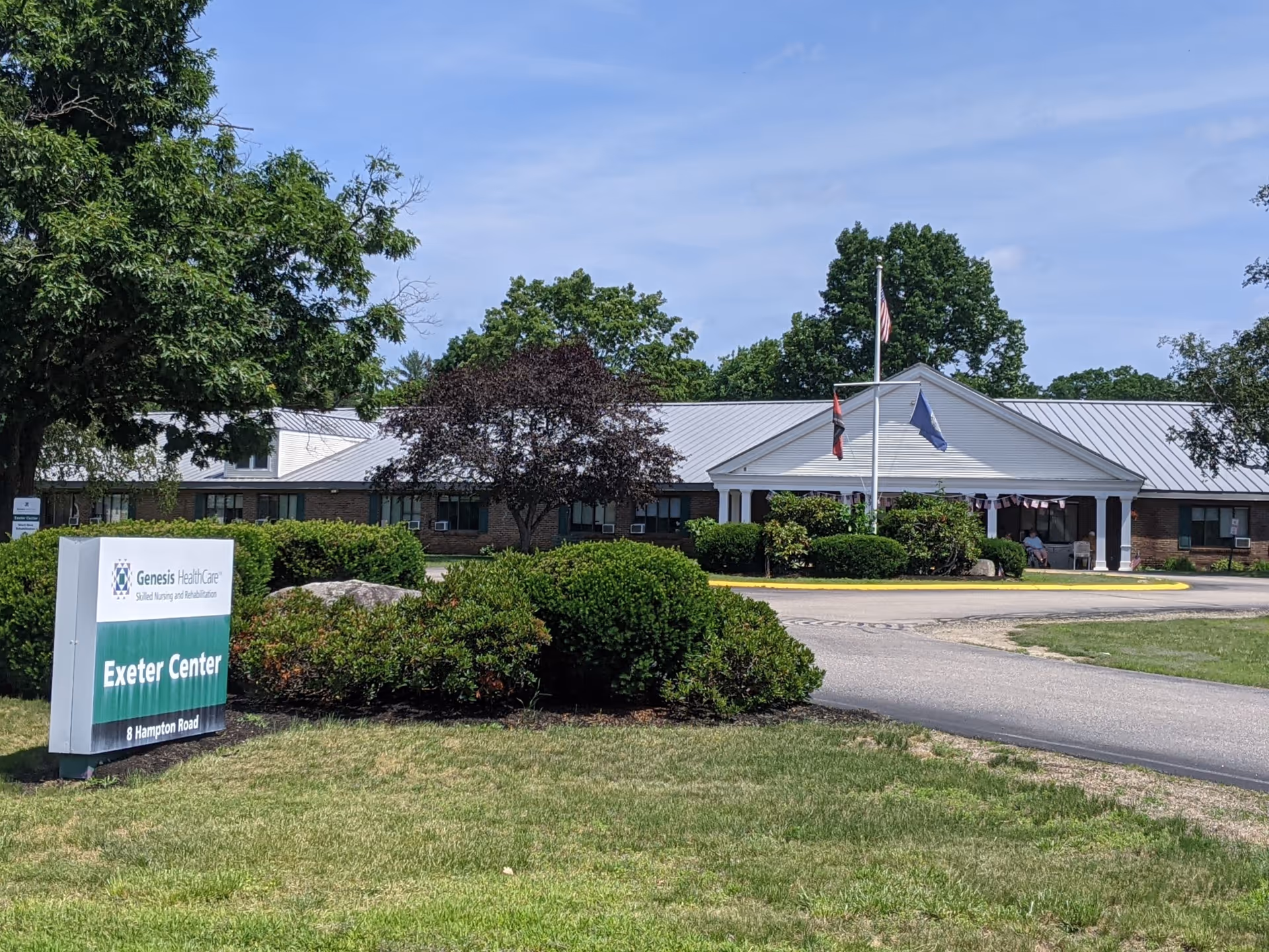Exterior view of Exeter Center facility with sign, entrance, flags, and landscaping.