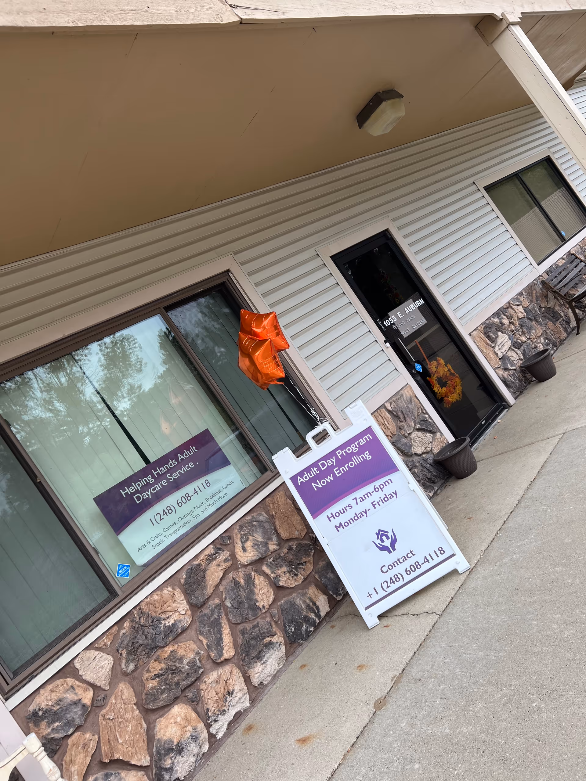 Exterior of a daycare facility with glass doors, stone facade, and enrollment signs.