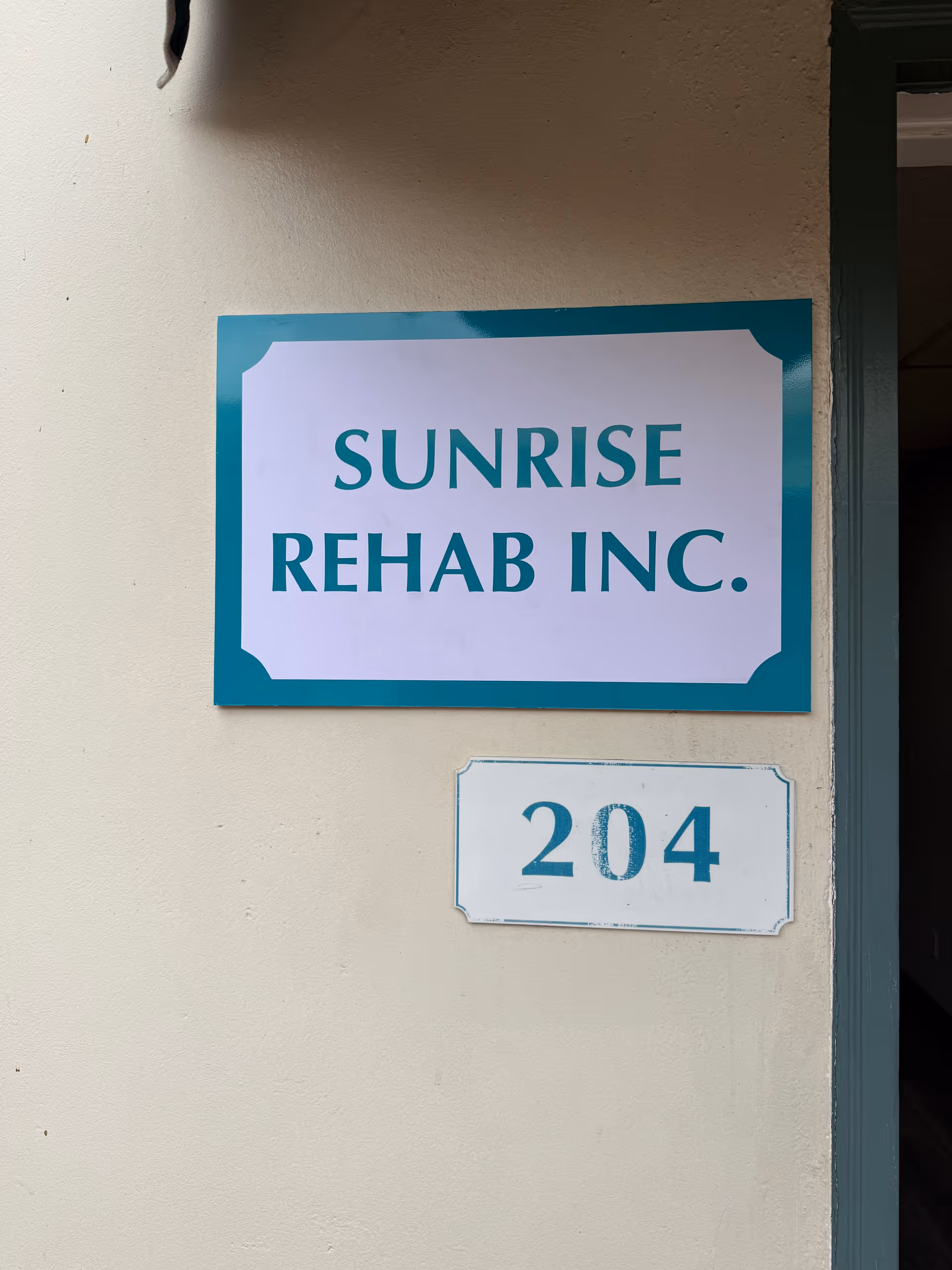 Exterior wall displaying Sunrise Rehab Inc. sign and the 204 doorway plaque.