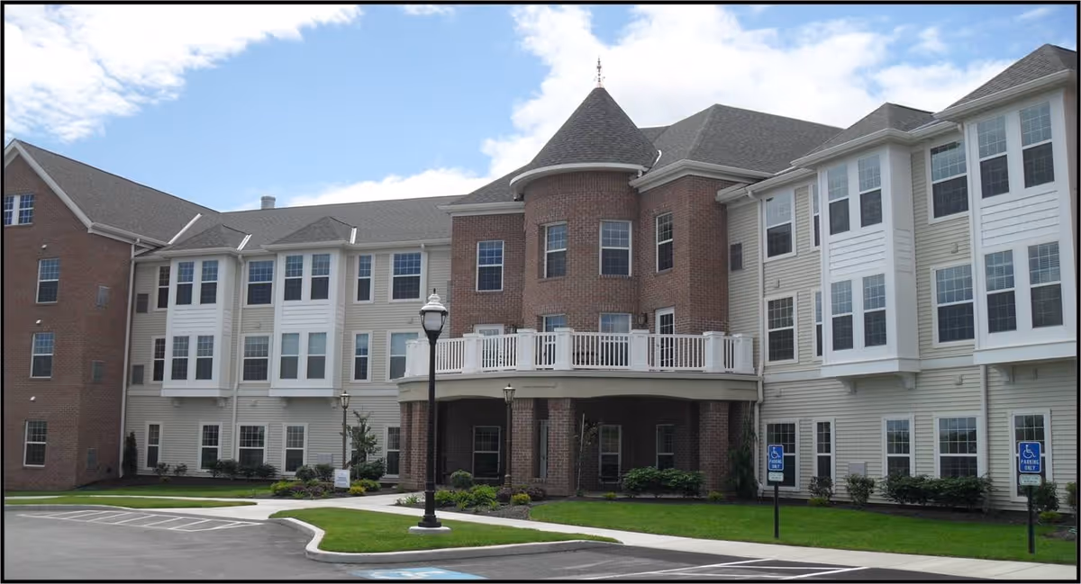 Front exterior of Woodlands at Hampton Woods, brick-and-siding senior living building with landscaping.