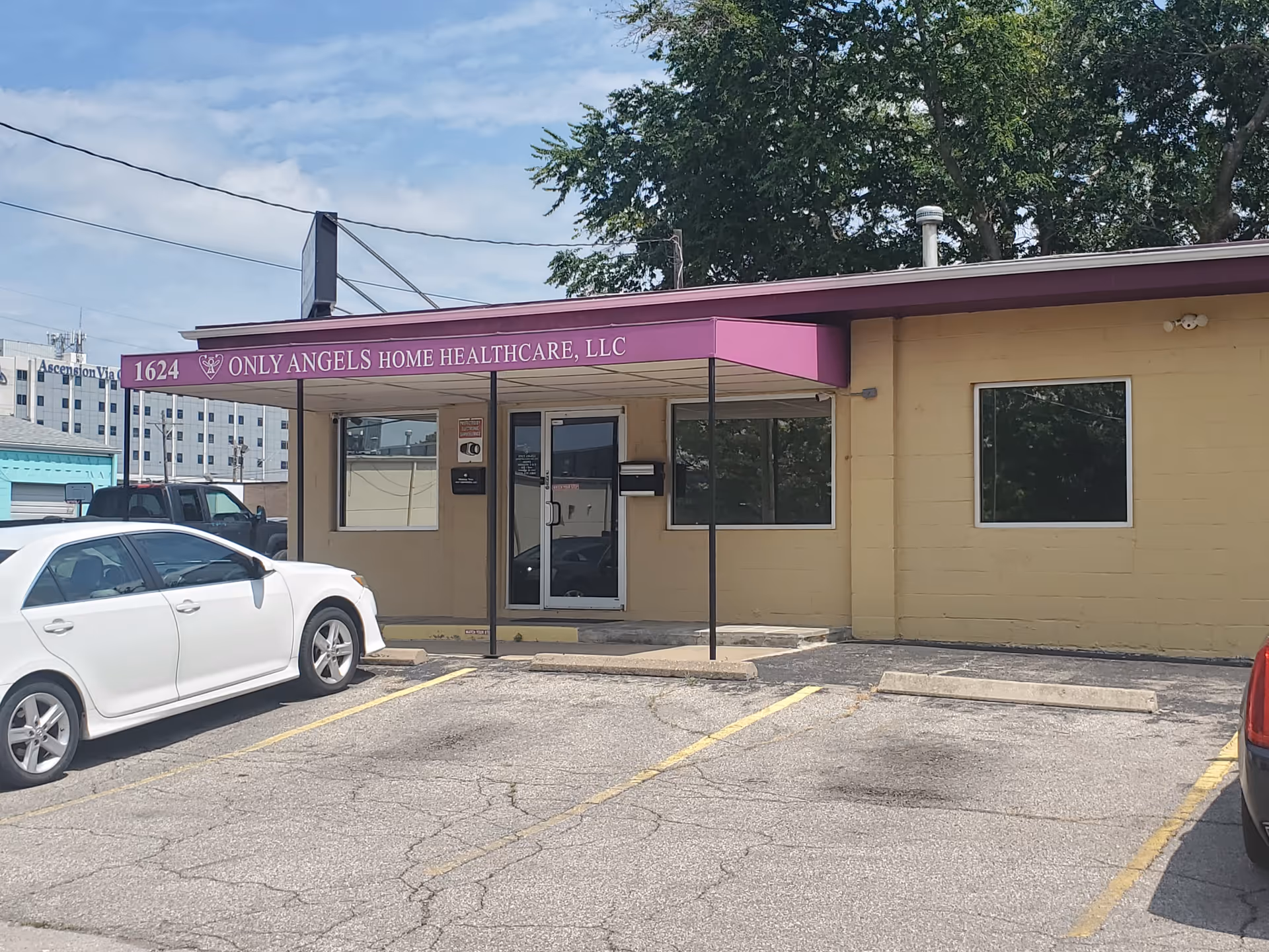 Front view of Only Angels Home Healthcare facility entrance with purple canopy and parked cars.