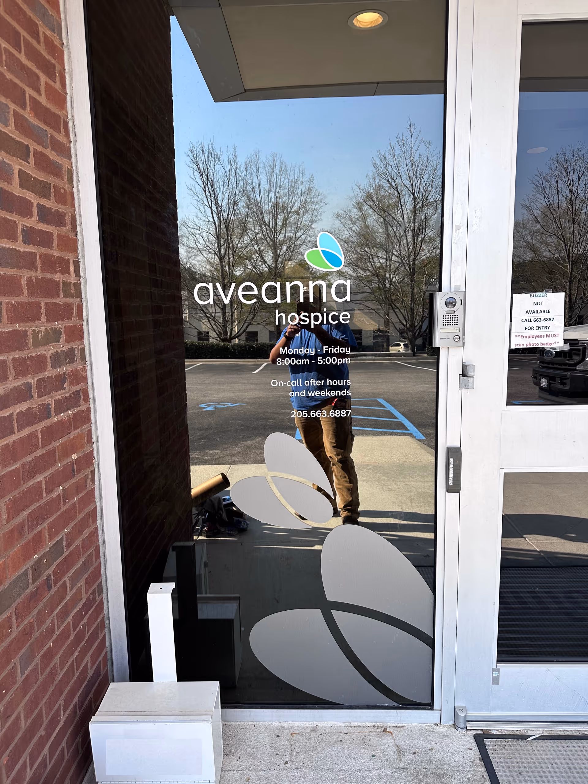 Glass entrance door with Aveanna Hospice logo and a reflection of a person.