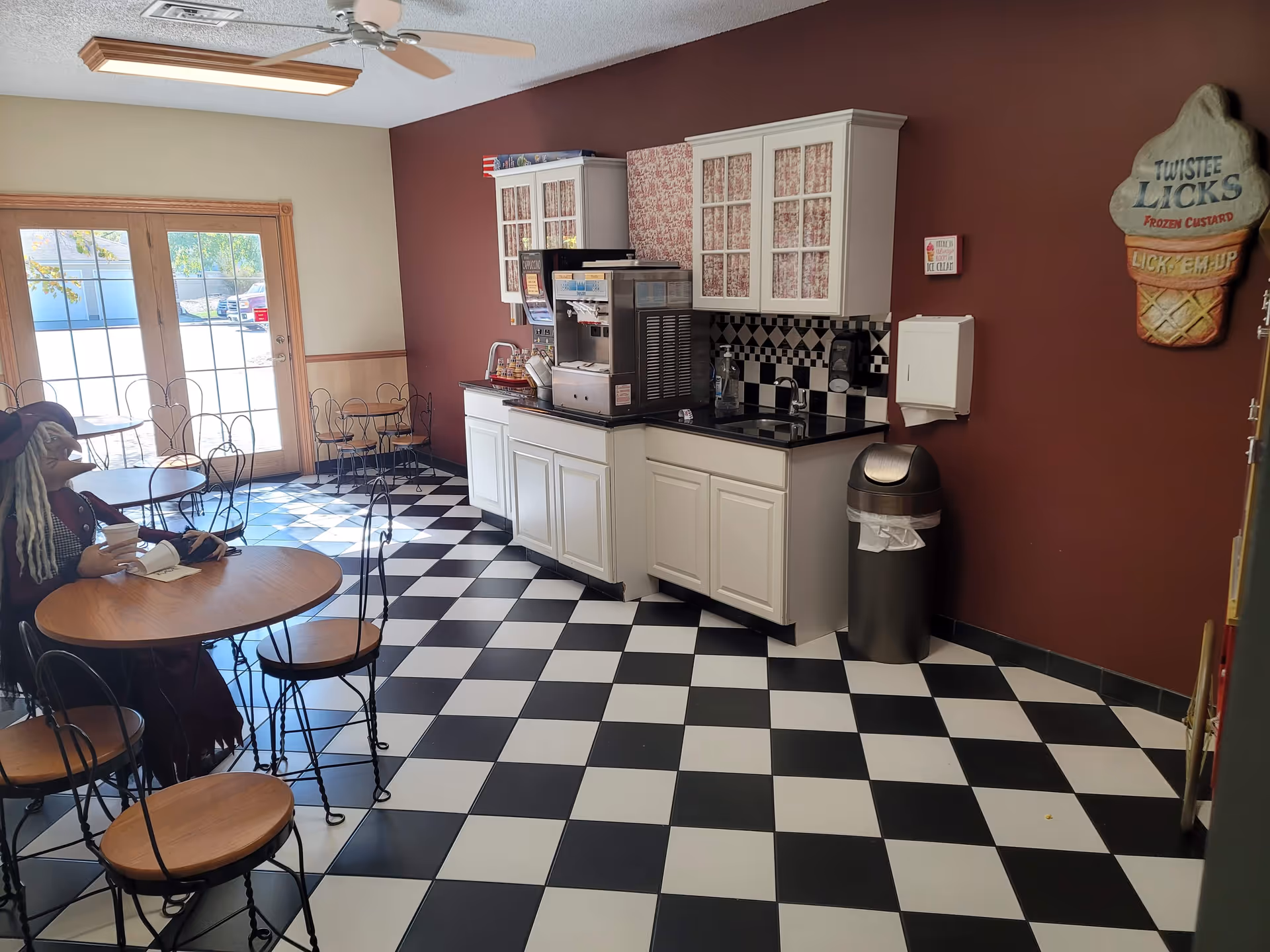 Diner-style lounge with checkered floor, coffee station, and ice-cream wall decor.