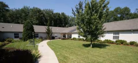 Single-story Brookdale South Bend facility exterior with curved walkway, lawn, and trees.