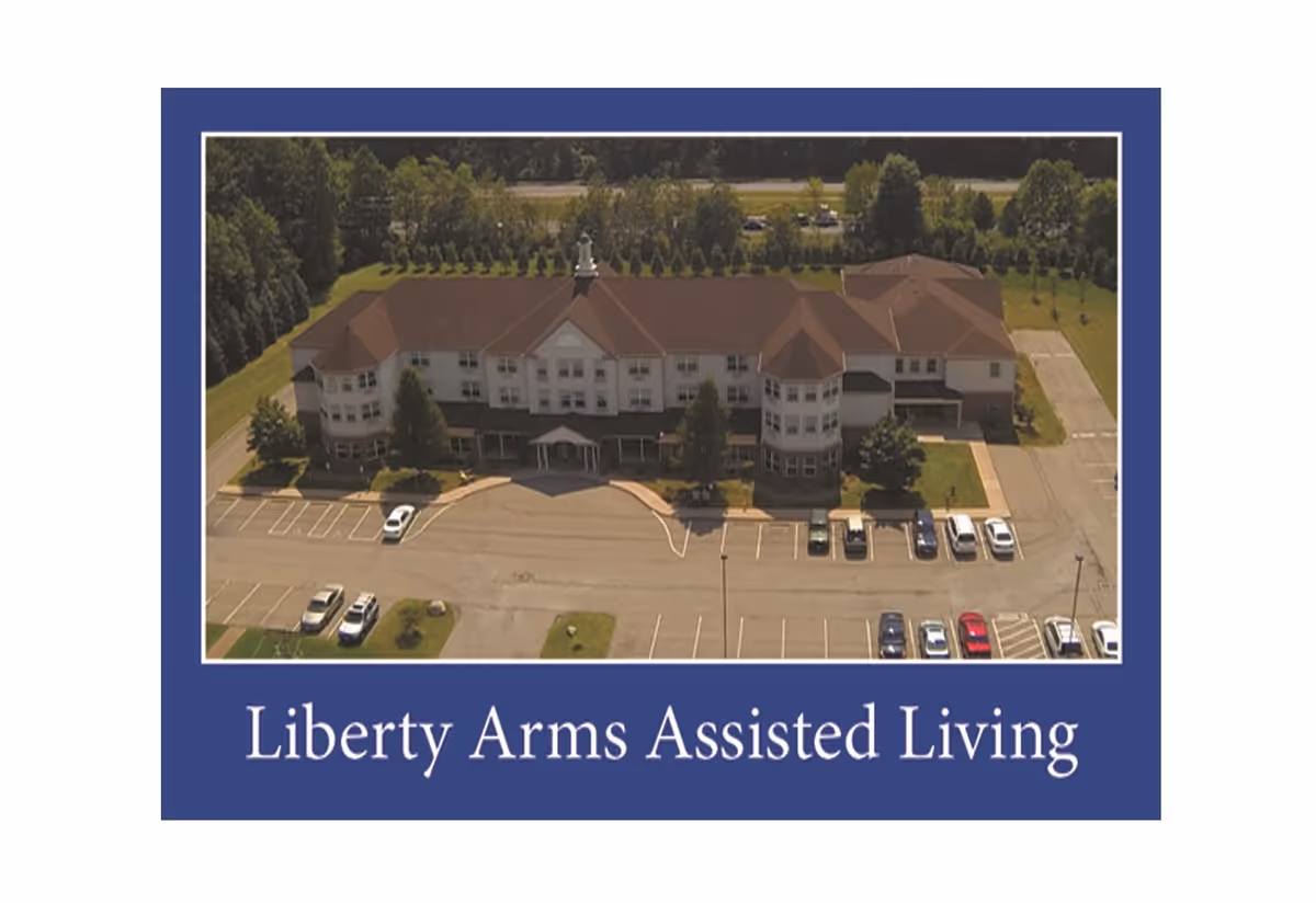 Aerial view of Liberty Arms Assisted Living building with a parking lot and surrounding trees.