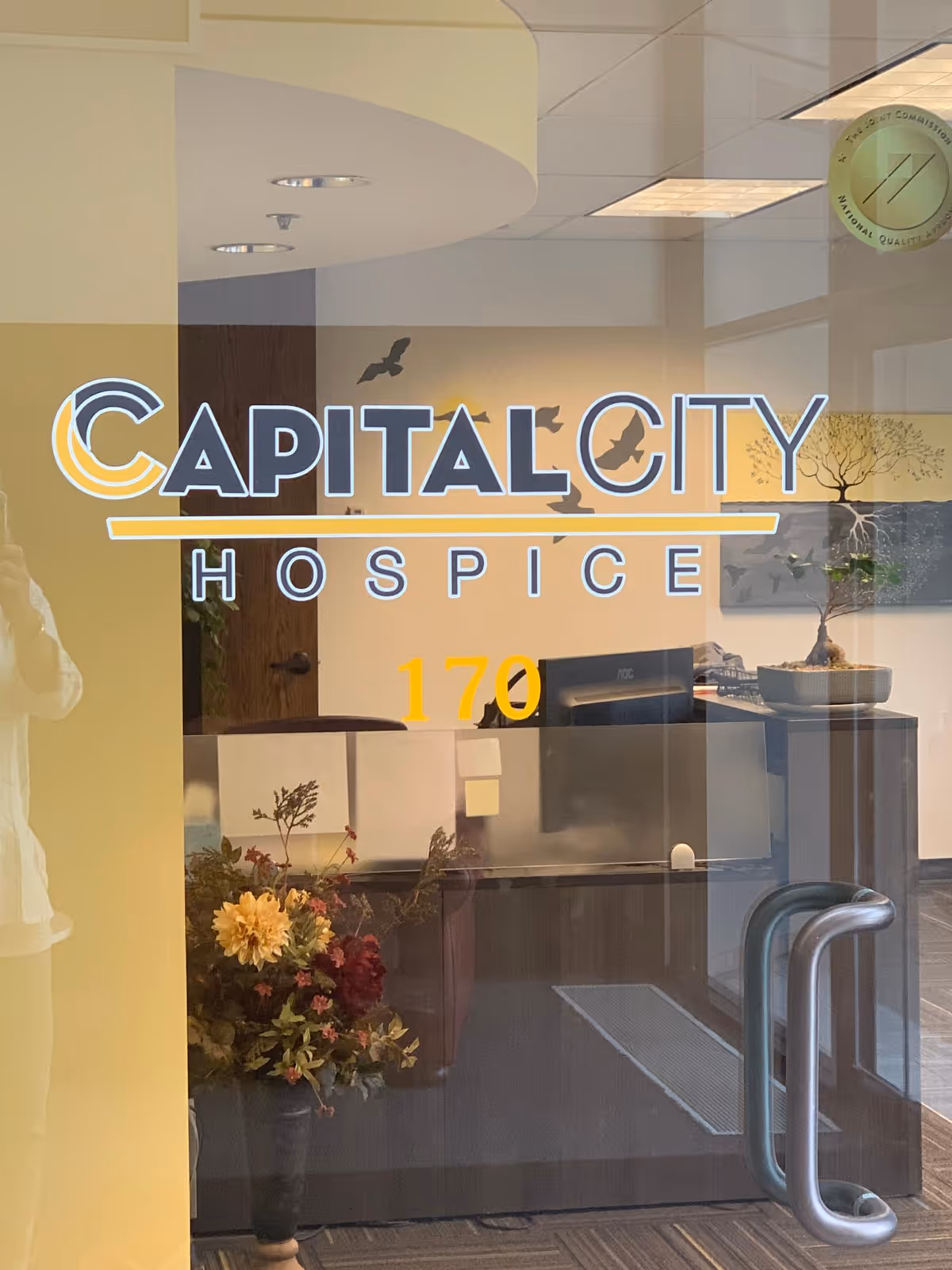 Interior view of Capital City Hospice lobby with reception desk and decorative plants.