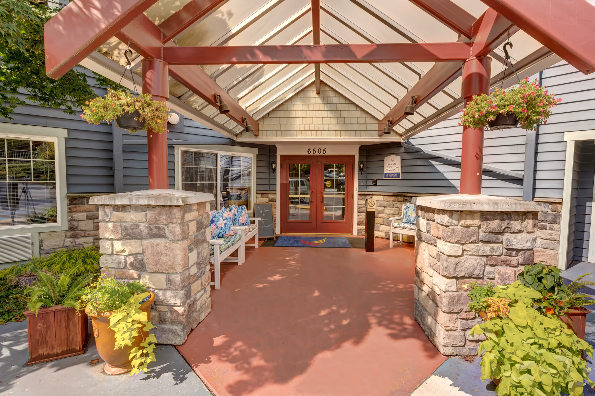 COGIR Senior Living entrance with stone pillars, benches, and hanging plants.