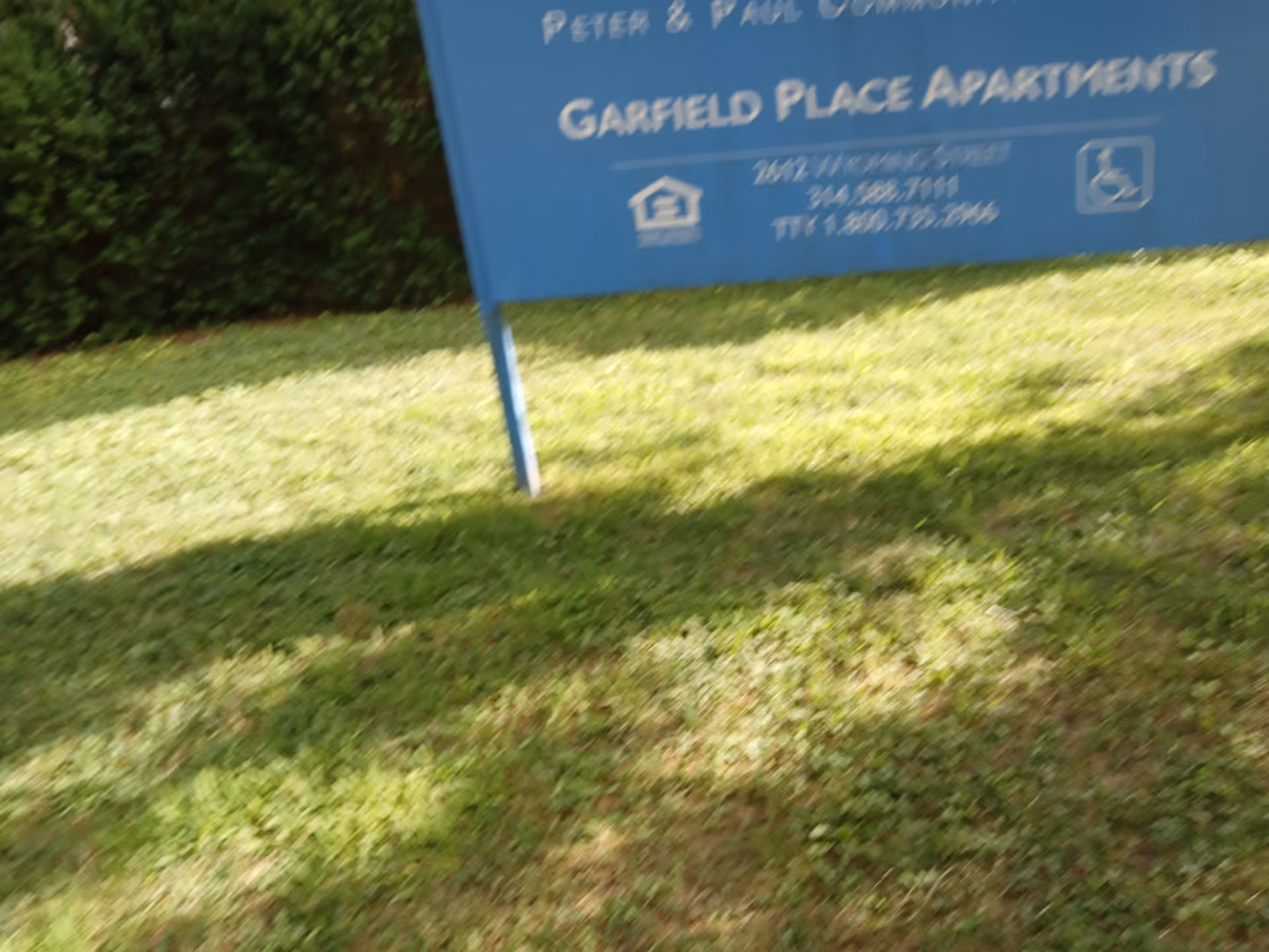 Blue Garfield Place Apartments sign on a grassy lawn with hedges.