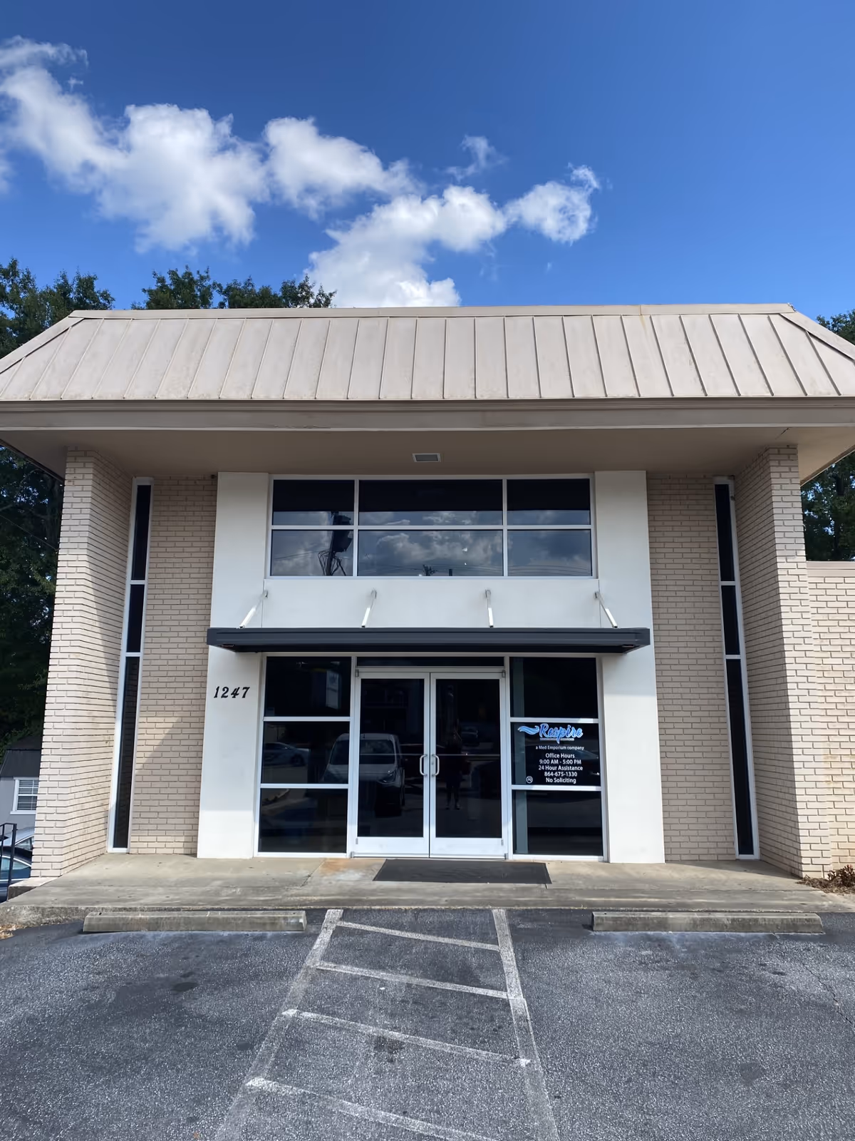 Modern building front of Respire Homecare Services Greenville with glass doors and parking.