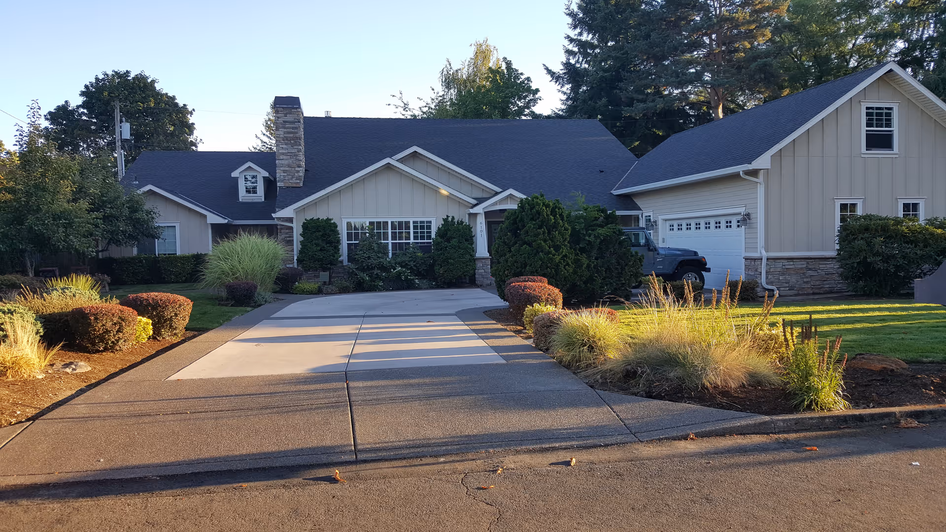 Front view of a single-story home with a long driveway and landscaped front yard.
