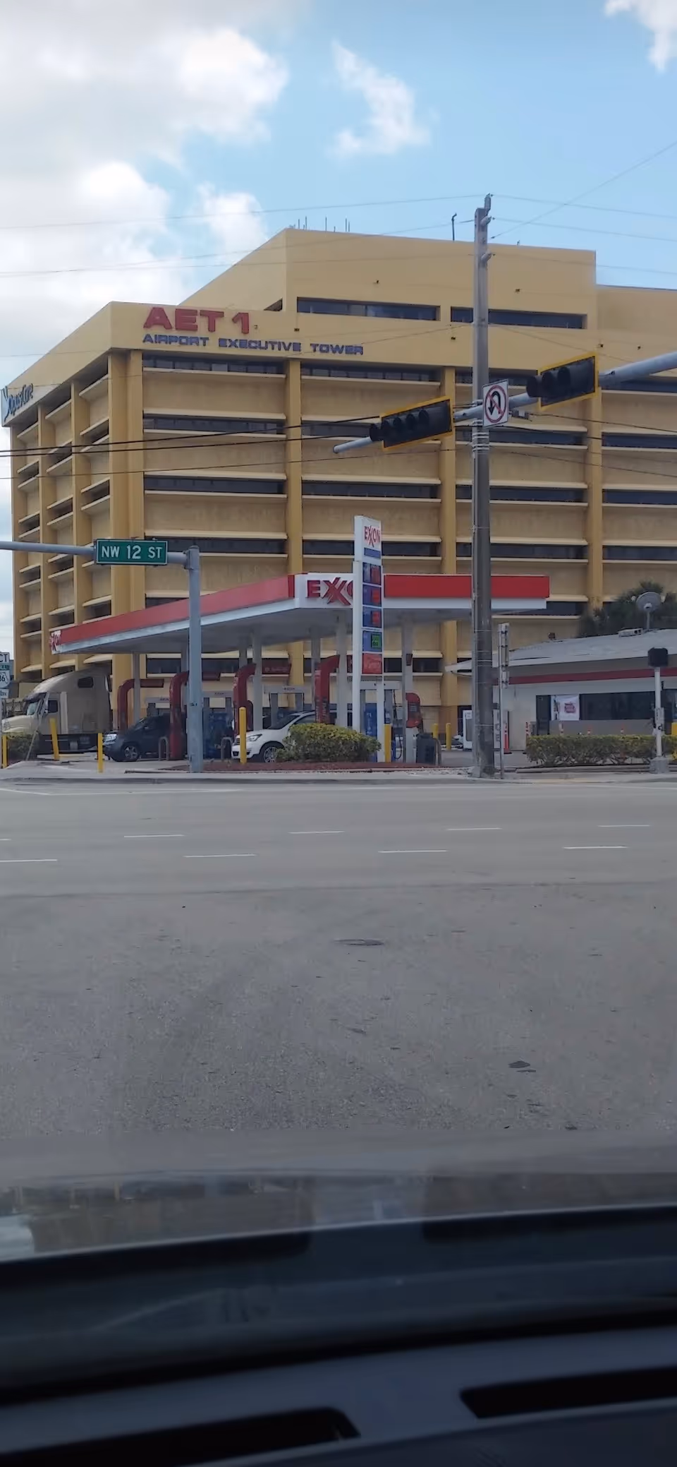 Yellow multi-story building labeled Airport Executive Tower with a gas station at street intersection