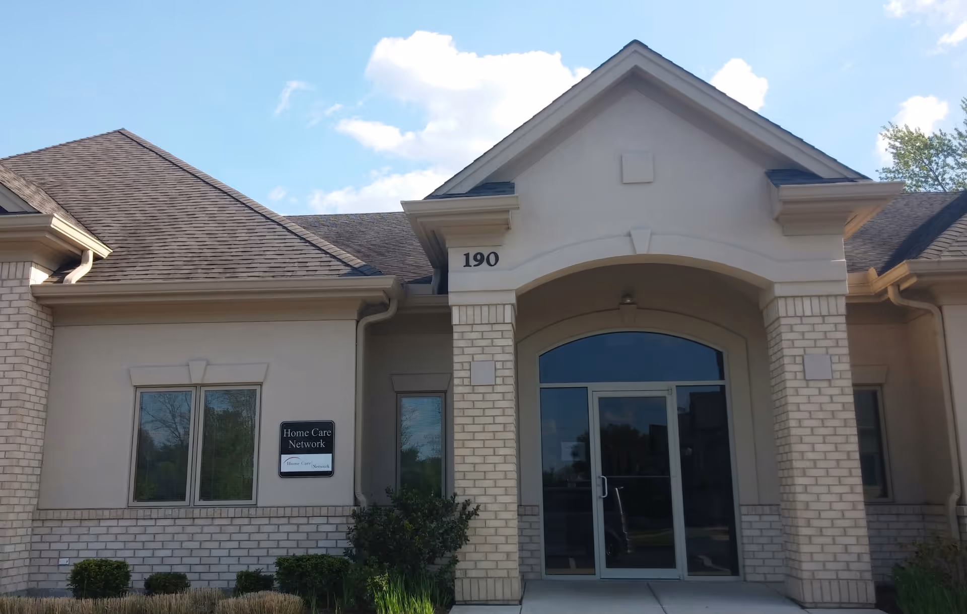 Front view of a senior living facility entrance with glass doors and brick columns