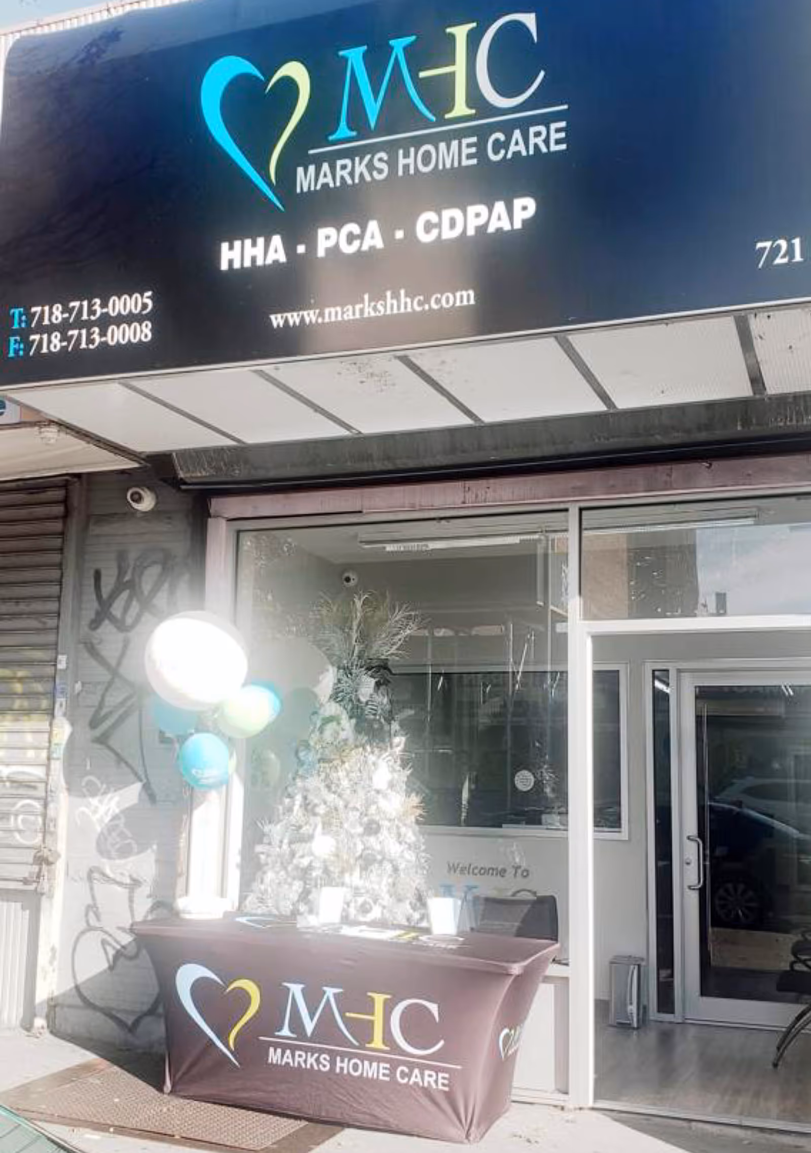 Exterior storefront of Marks Home Care with sign, glass door, and holiday display.