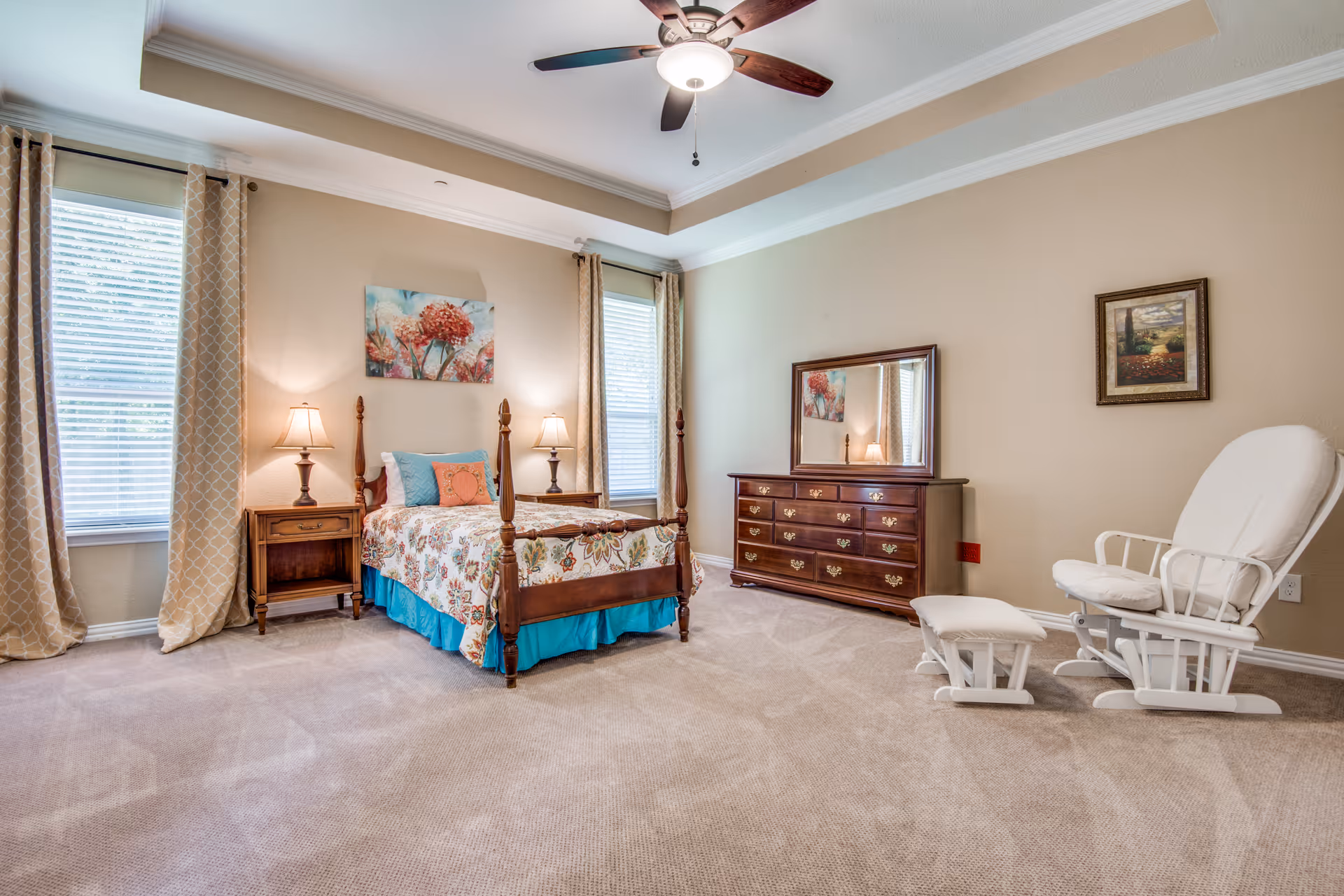 A spacious bedroom featuring a four-poster bed, dresser, and white reclining chair.