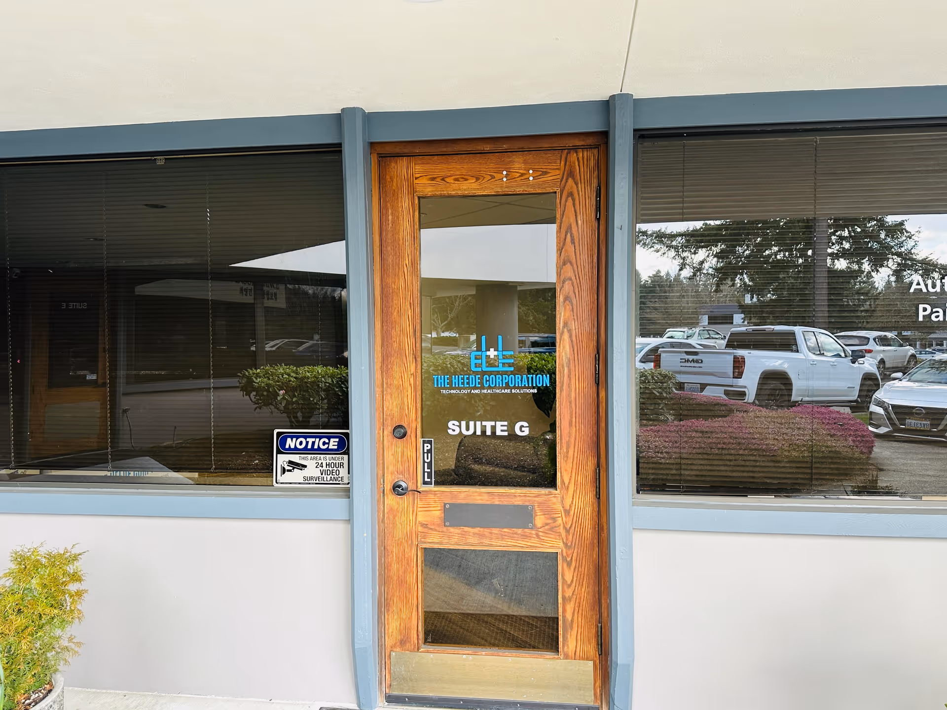 Wood door with glass panel shows The Heede Corporation logo and Suite G.
