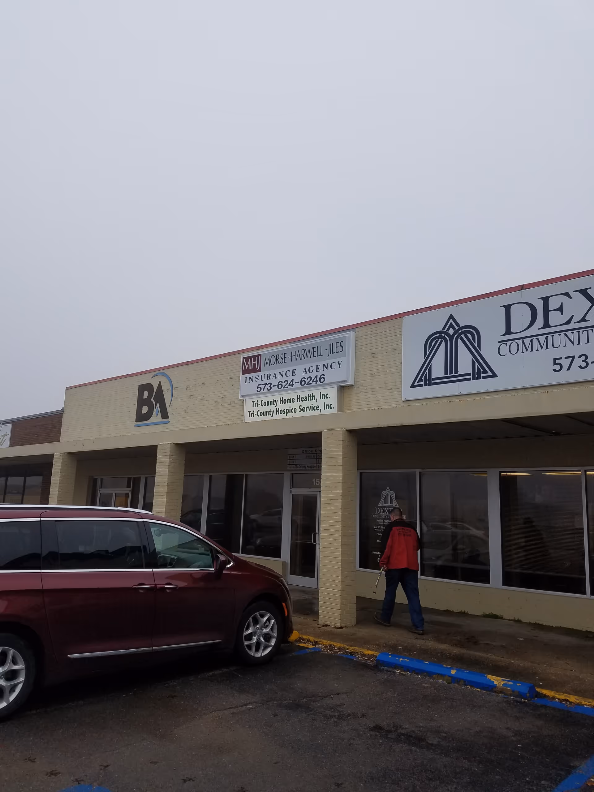 Beige strip mall exterior with signs for Tri-County Hospice and a nearby insurance agency.