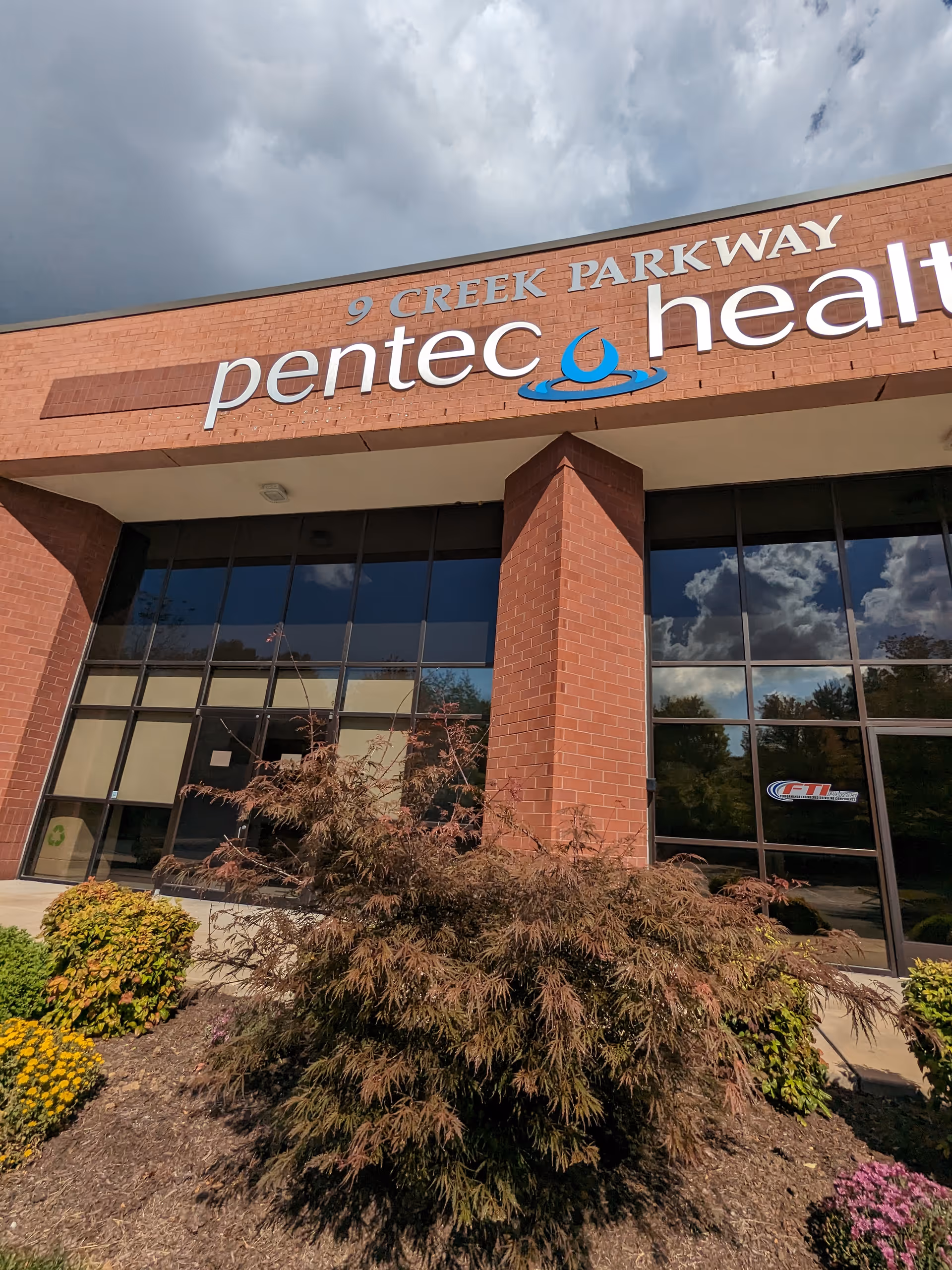 Exterior view of Pentec Health building with brick facade and landscaped plants.