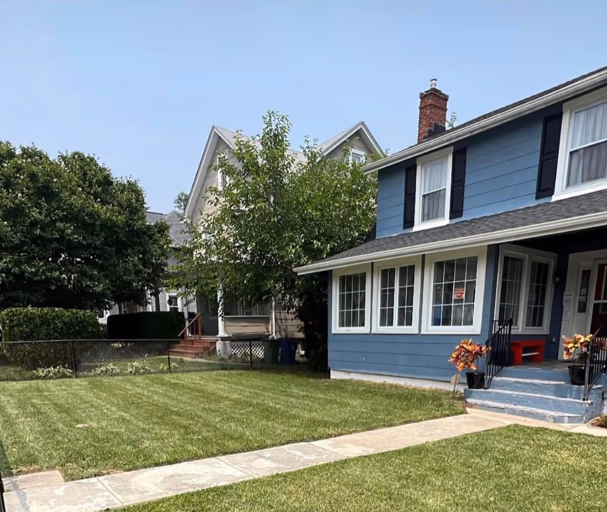 Blue two-story house with white trim, front lawn, and walkway.