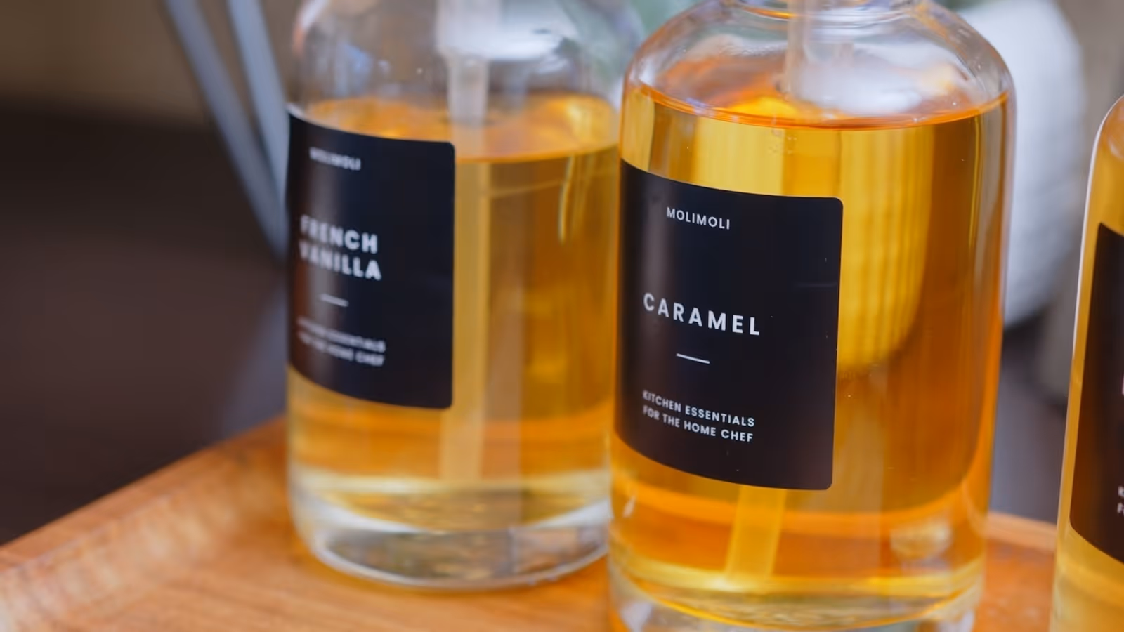 Close-up view of three glass bottles containing flavored liquids labeled French Vanilla, Caramel, and another flavor, placed on a wooden tray.