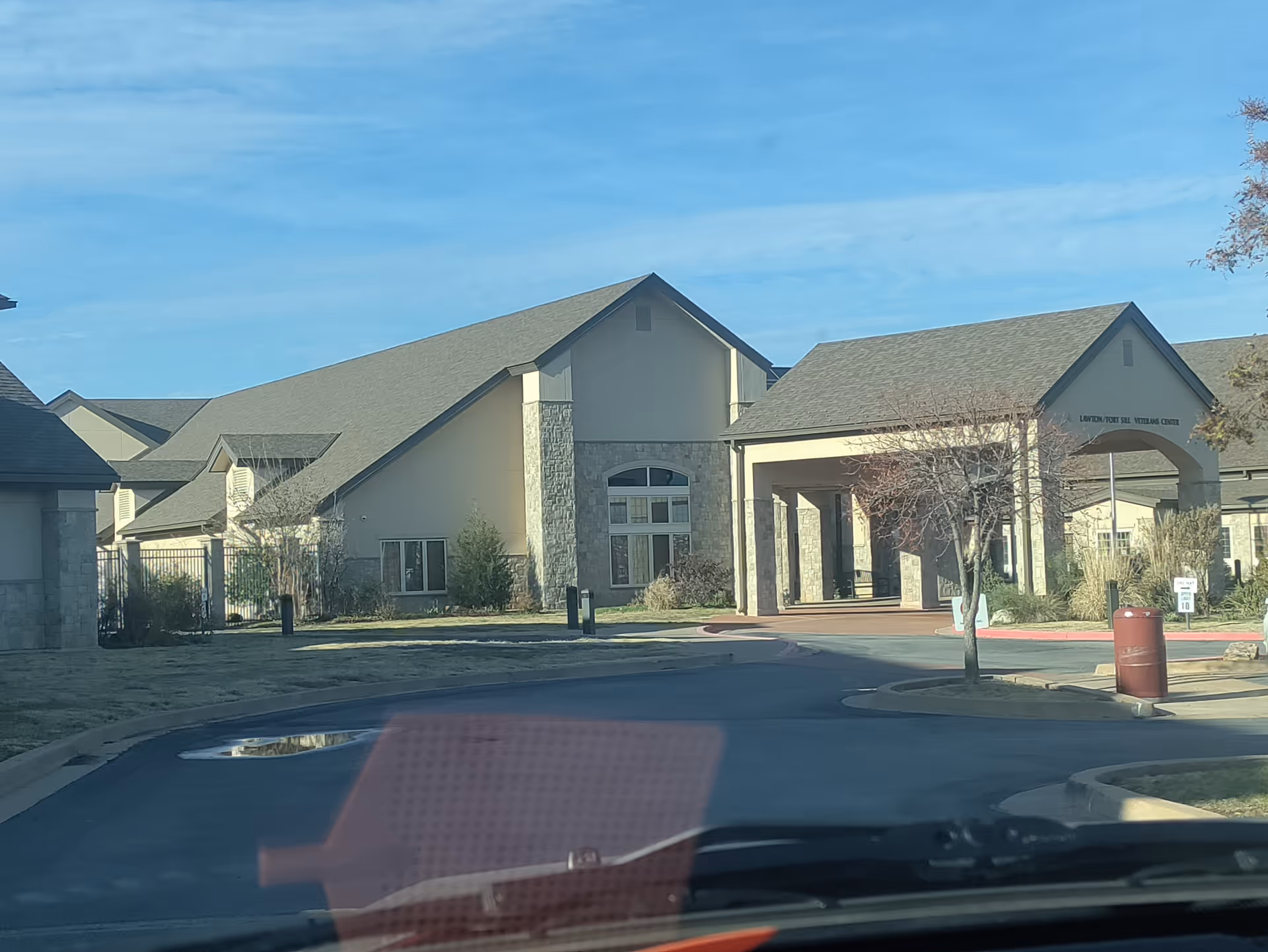 Front view of Lawton Fort Sill Veterans Center with covered entrance, stone facade, and driveway.