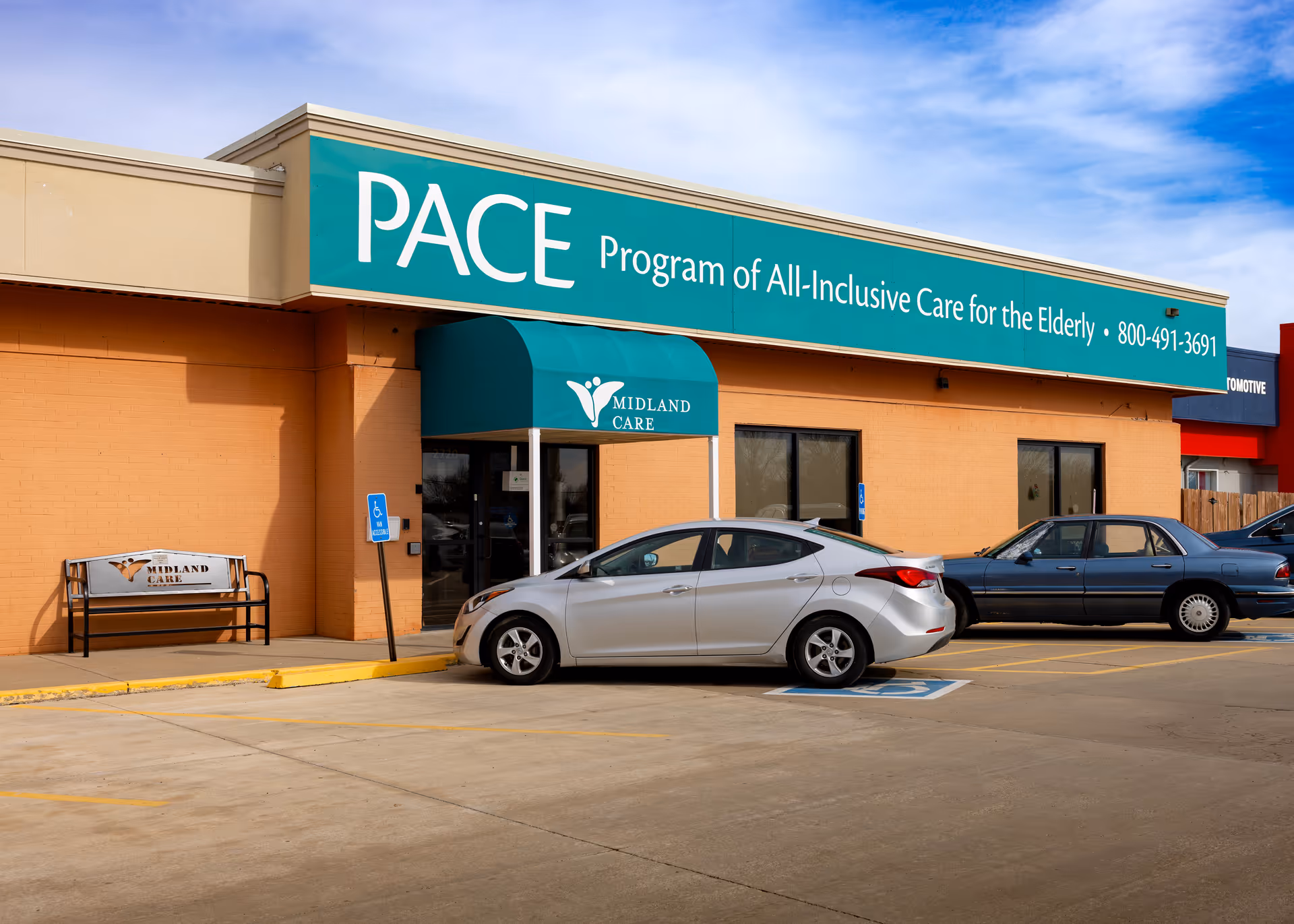 Exterior view of Midland Care PACE building with teal sign and parked cars.