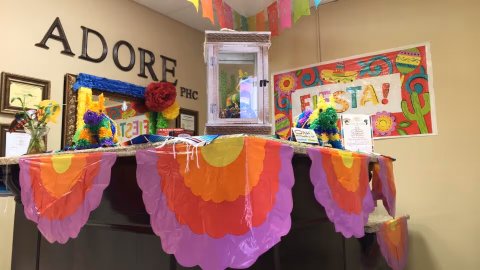 Decorated reception desk inside Adore Primary Home Care with Fiesta banner and colorful streamers.