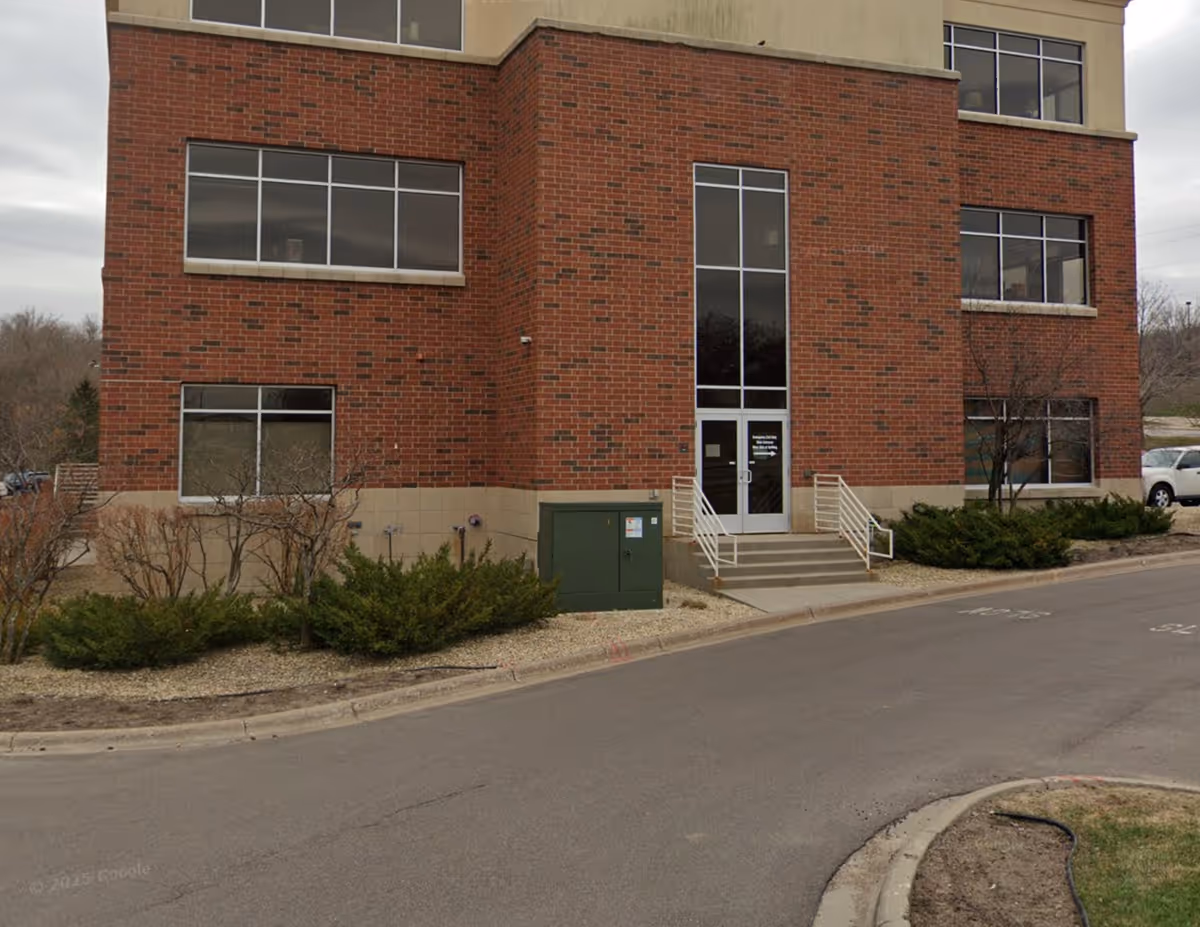 Brick, multi-story facility with a glass entrance and landscaped front shrubs.