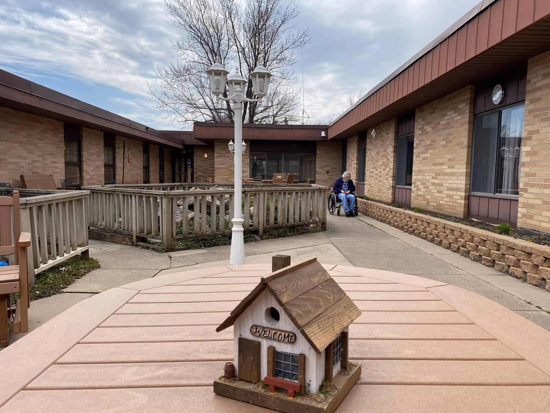 Outdoor courtyard of River Valley Health and Rehabilitation Center with a wheelchair resident near the building.
