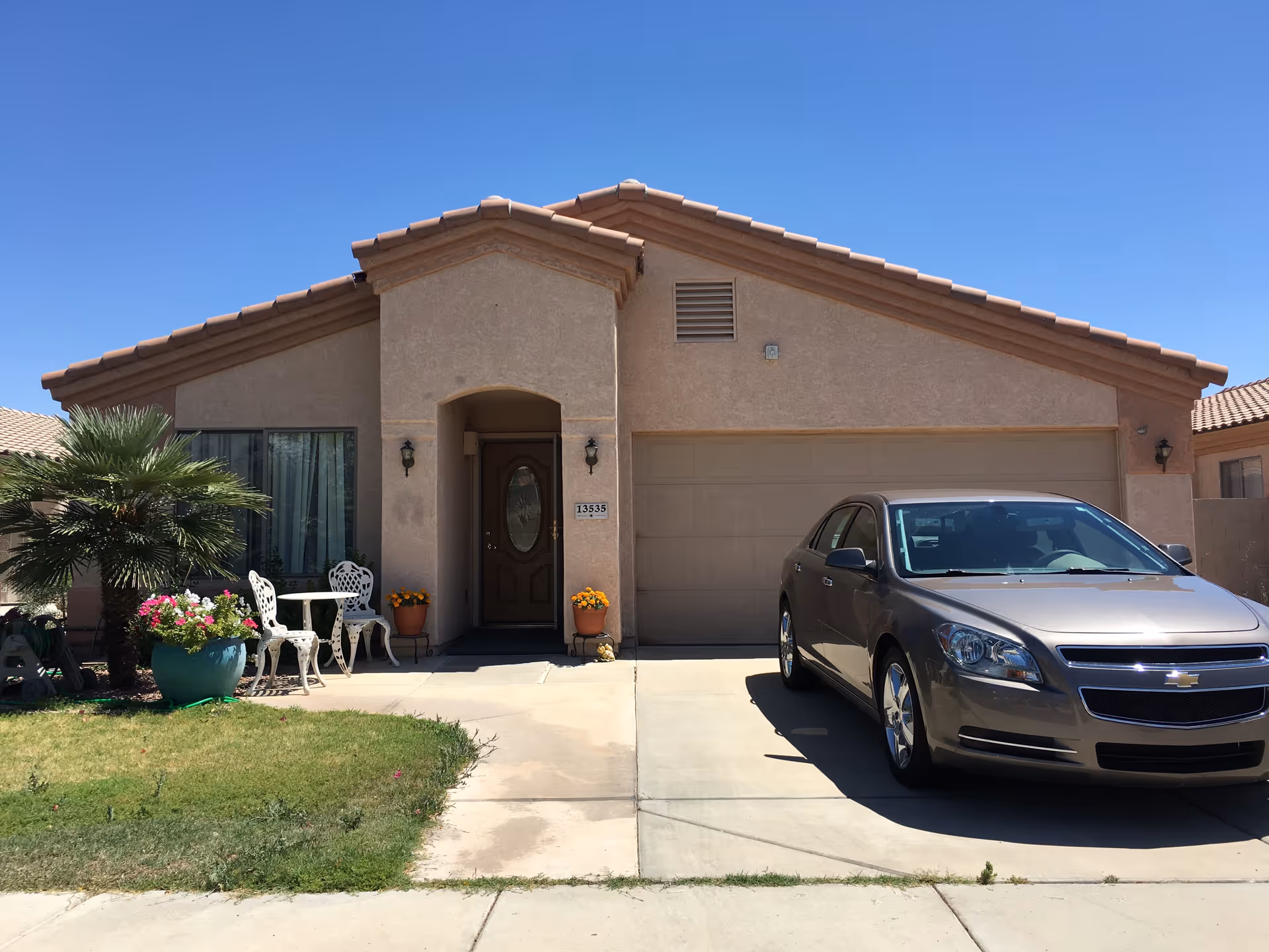 Front view of Desert Palms Adult Care Home: beige single-story house with garage and parked car.