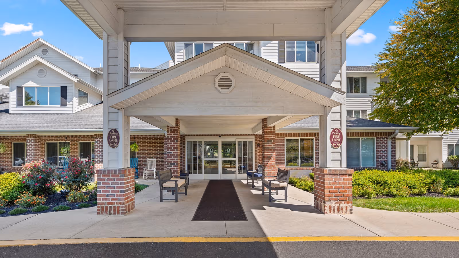 Exterior view of Holiday Essex House entrance with brick columns, a covered drive, and benches.