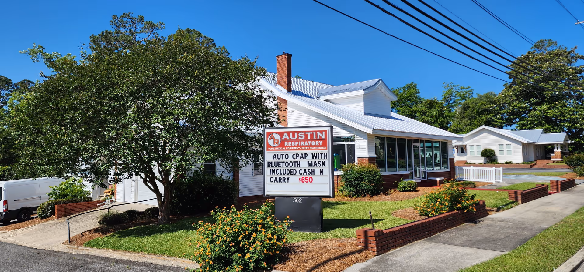 Exterior view of a white facility with Austin Respiratory sign and landscaped front yard.
