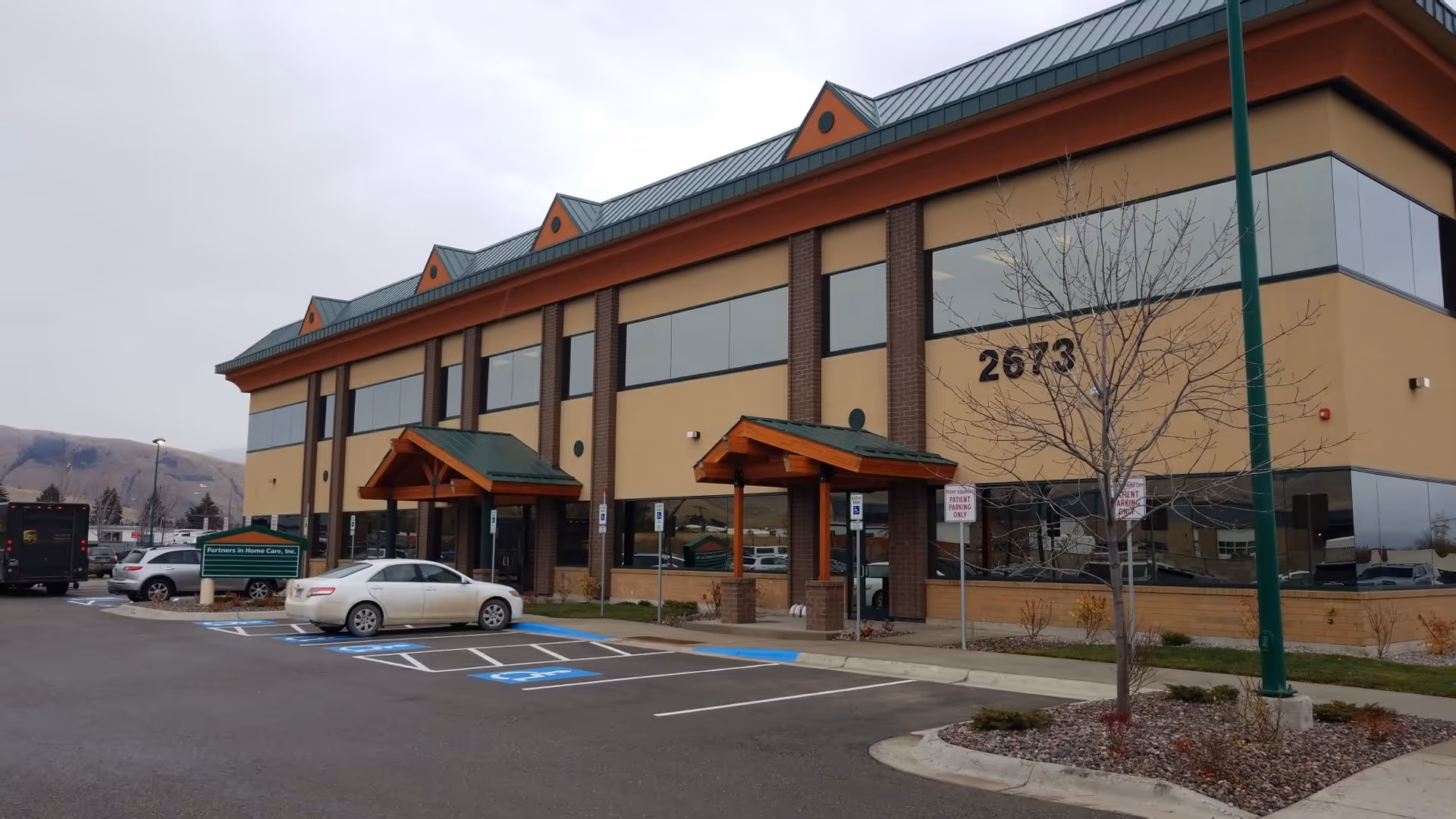 Front view of Partners In Home Care building with beige walls, green roof, and parking lot.