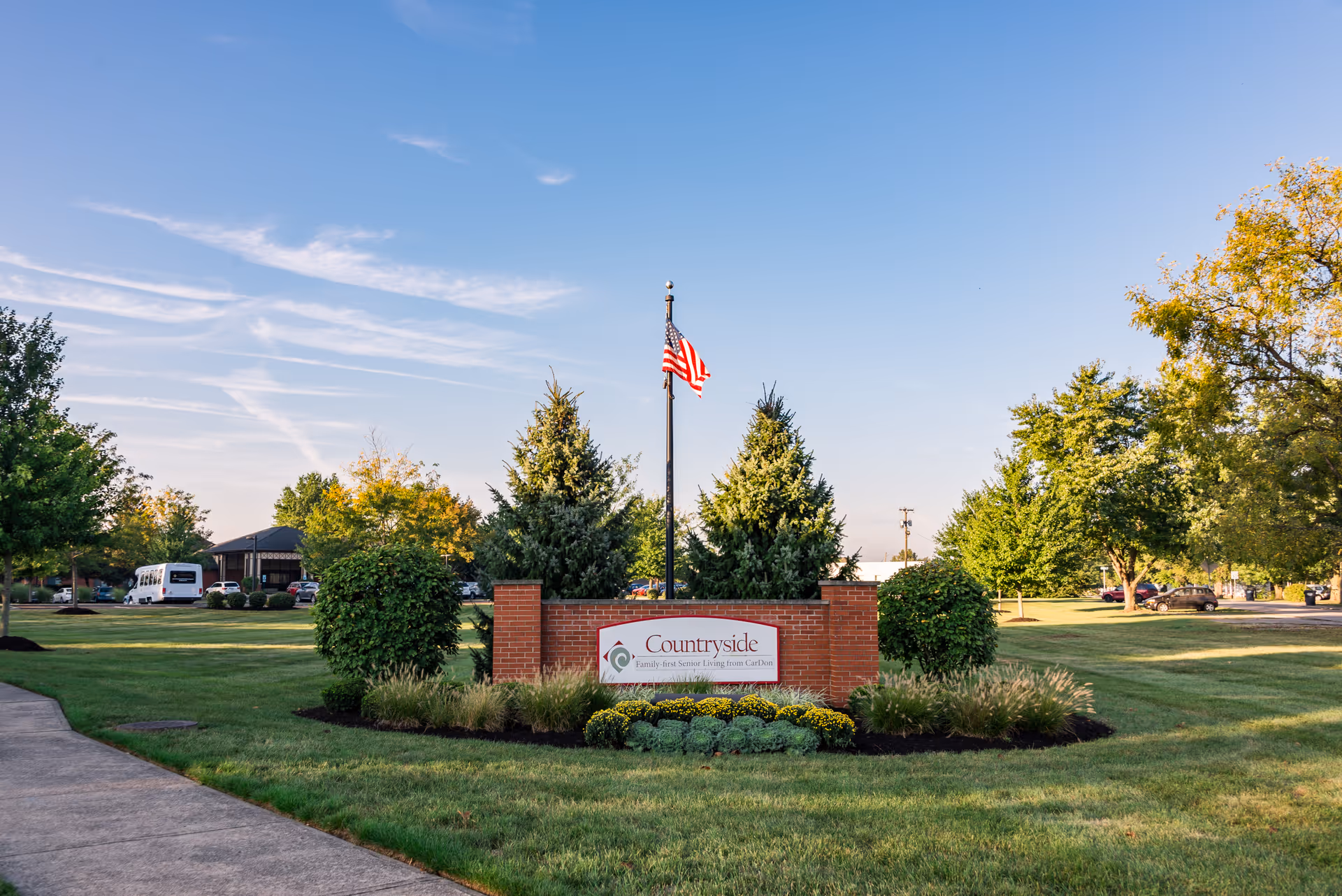 Exterior view of Countryside Manor Health & Living Community sign, flagpole, and landscaped entrance.