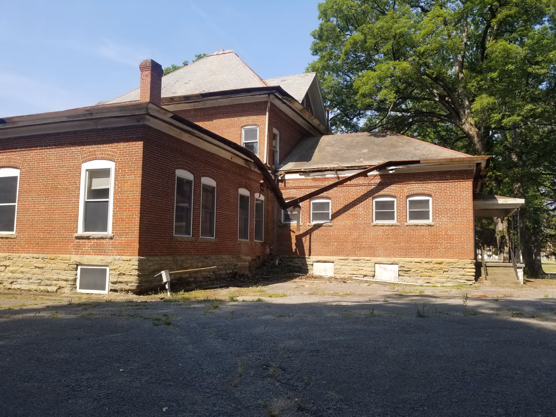 Exterior view of a brick Indiana Veterans' Home building with a collapsed roof and trees nearby