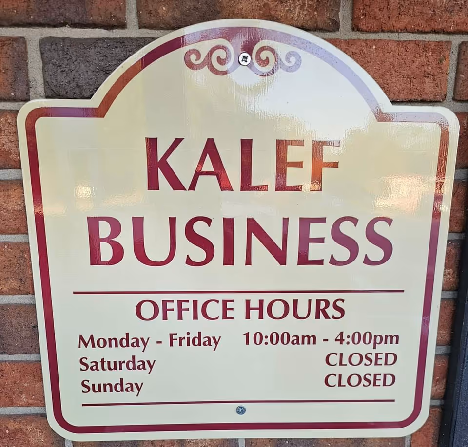 KALEF Business Office Hours sign mounted on a brick wall.